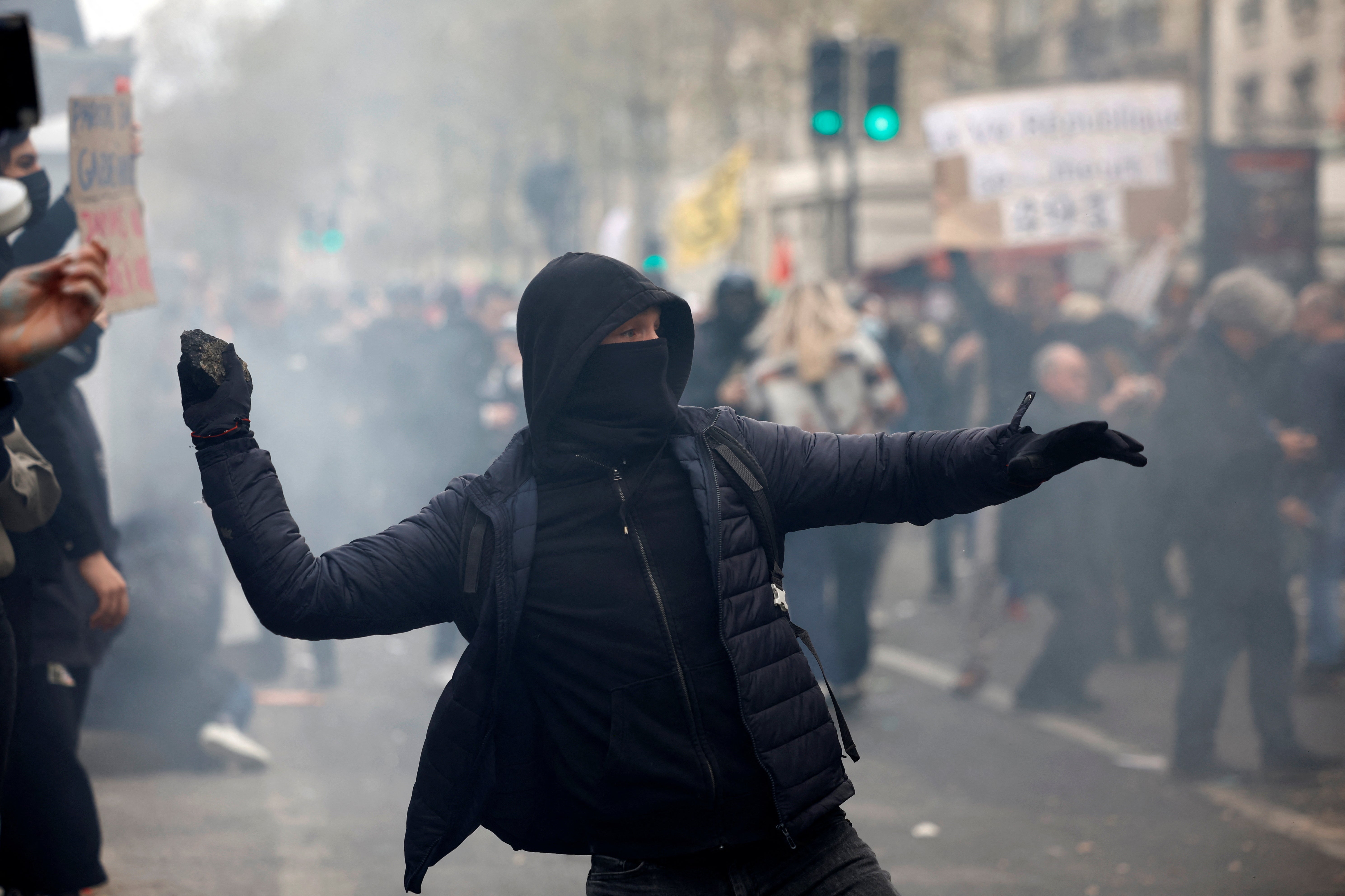 A protester throws a stone at riot police in Paris