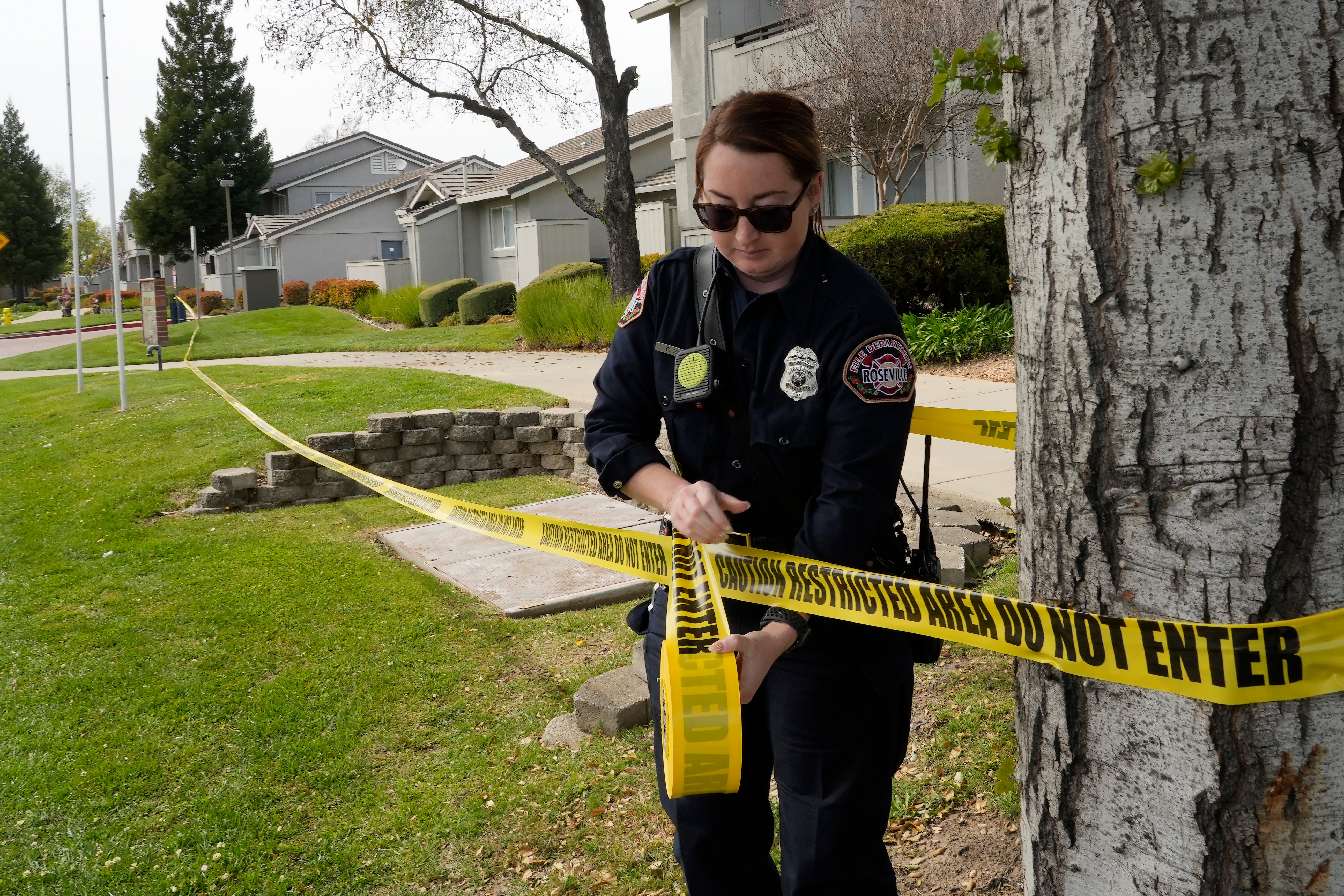 Roseville Fire Inspector Chelsea Zinc puts up barrier tape across the street from a local fitness centre and library where a lockdown occurred in response to the shooting