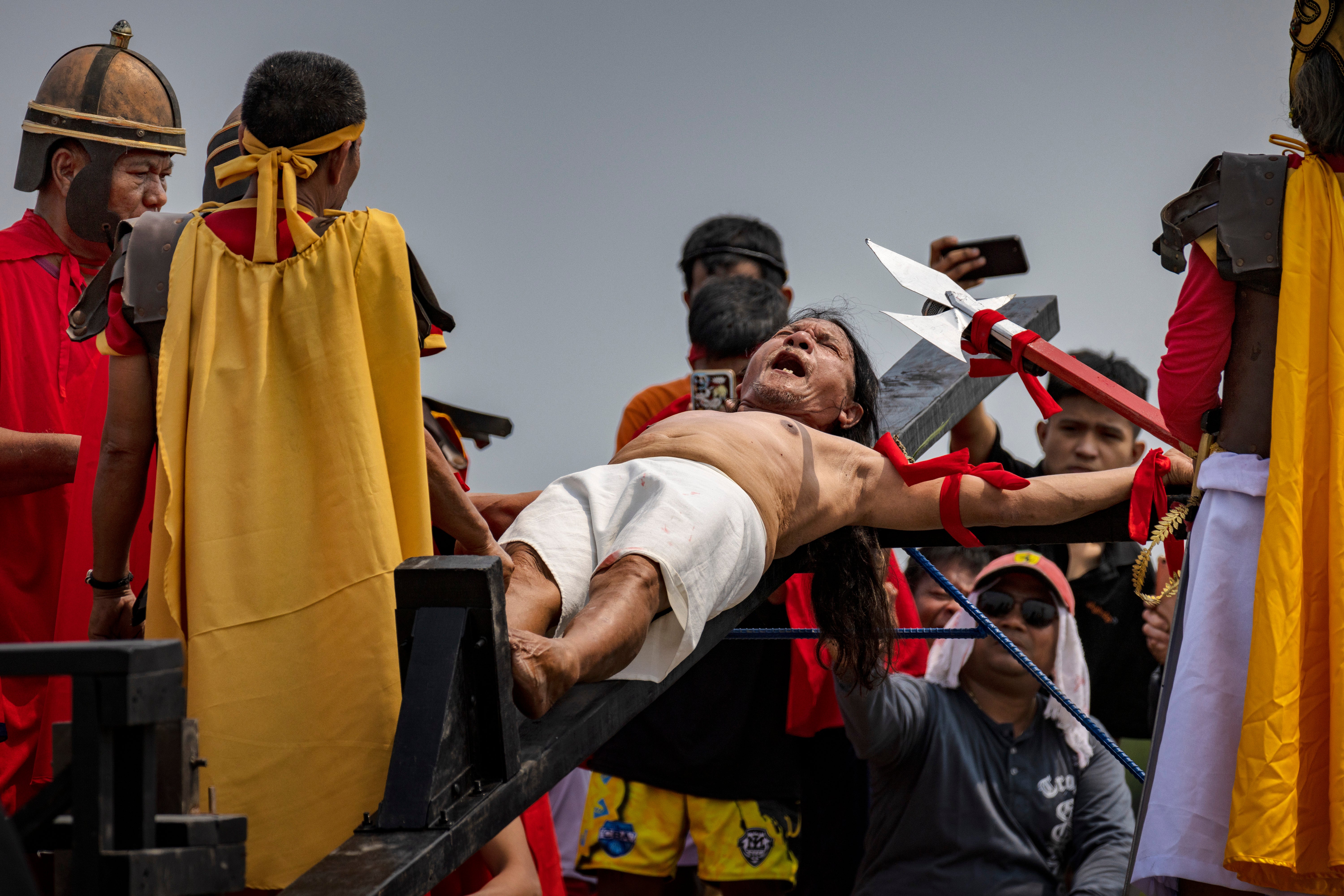 Penitent Ruben Enaje grimaces in pain as he is nailed to a cross during Good Friday crucifixions in San Fernando, Pampanga, Philippines