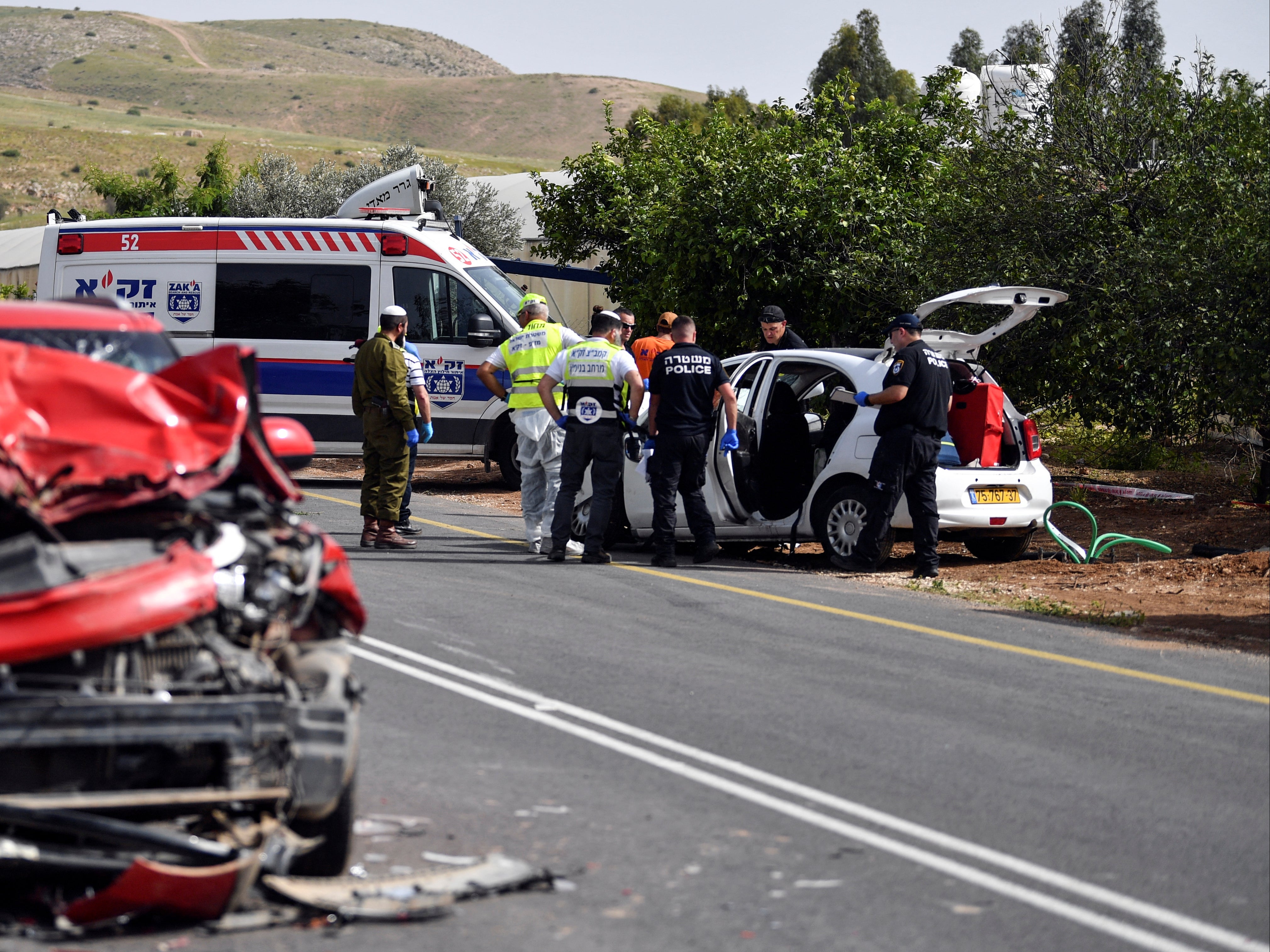 Israeli medics and policemen check a damaged car at the scene of a shooting attack, in the Jordan Valley in the Israeli-occupied West Bank