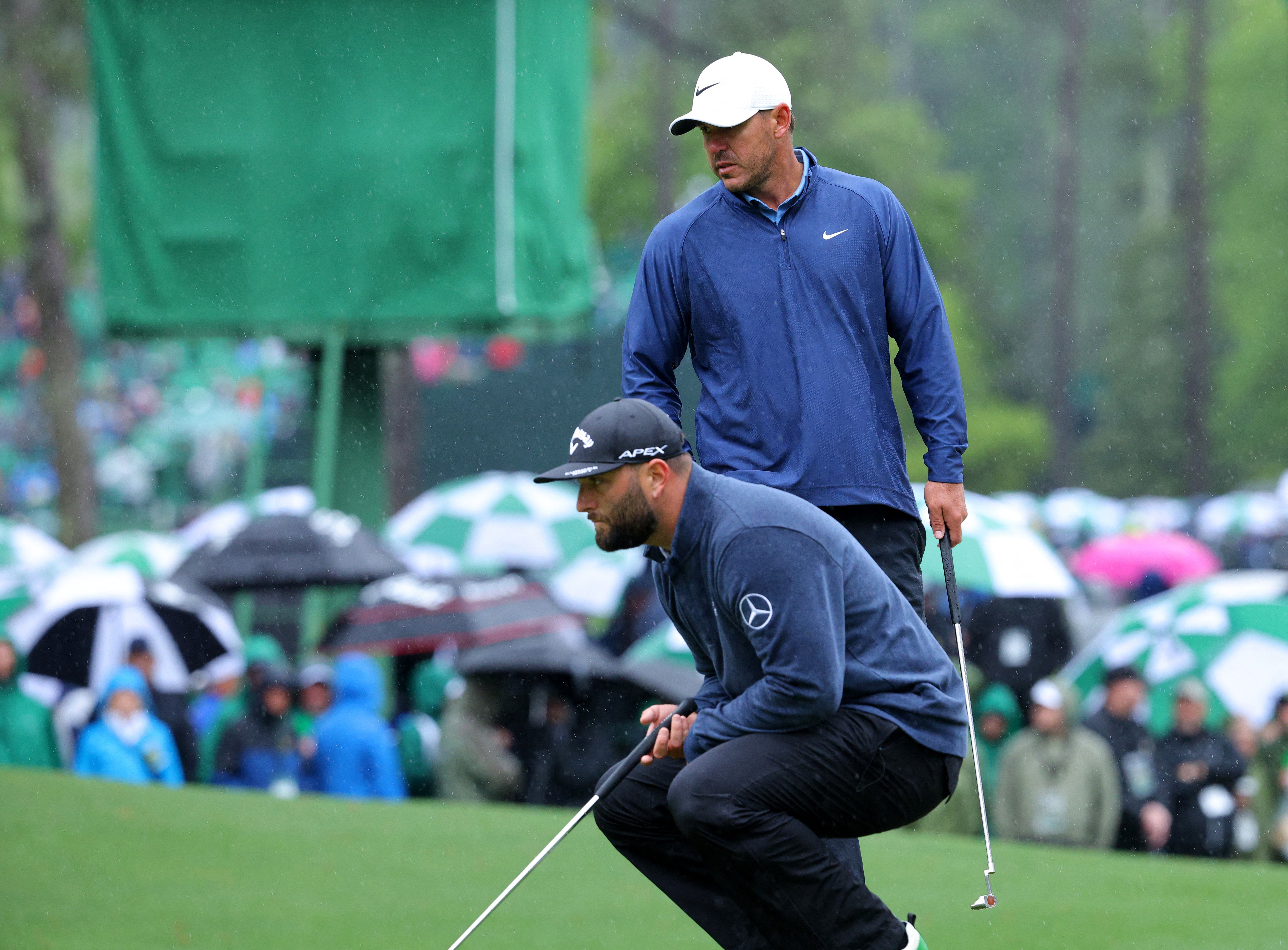 Jon Rahm and Brooks Koepka, above, eye the hole on sixth green