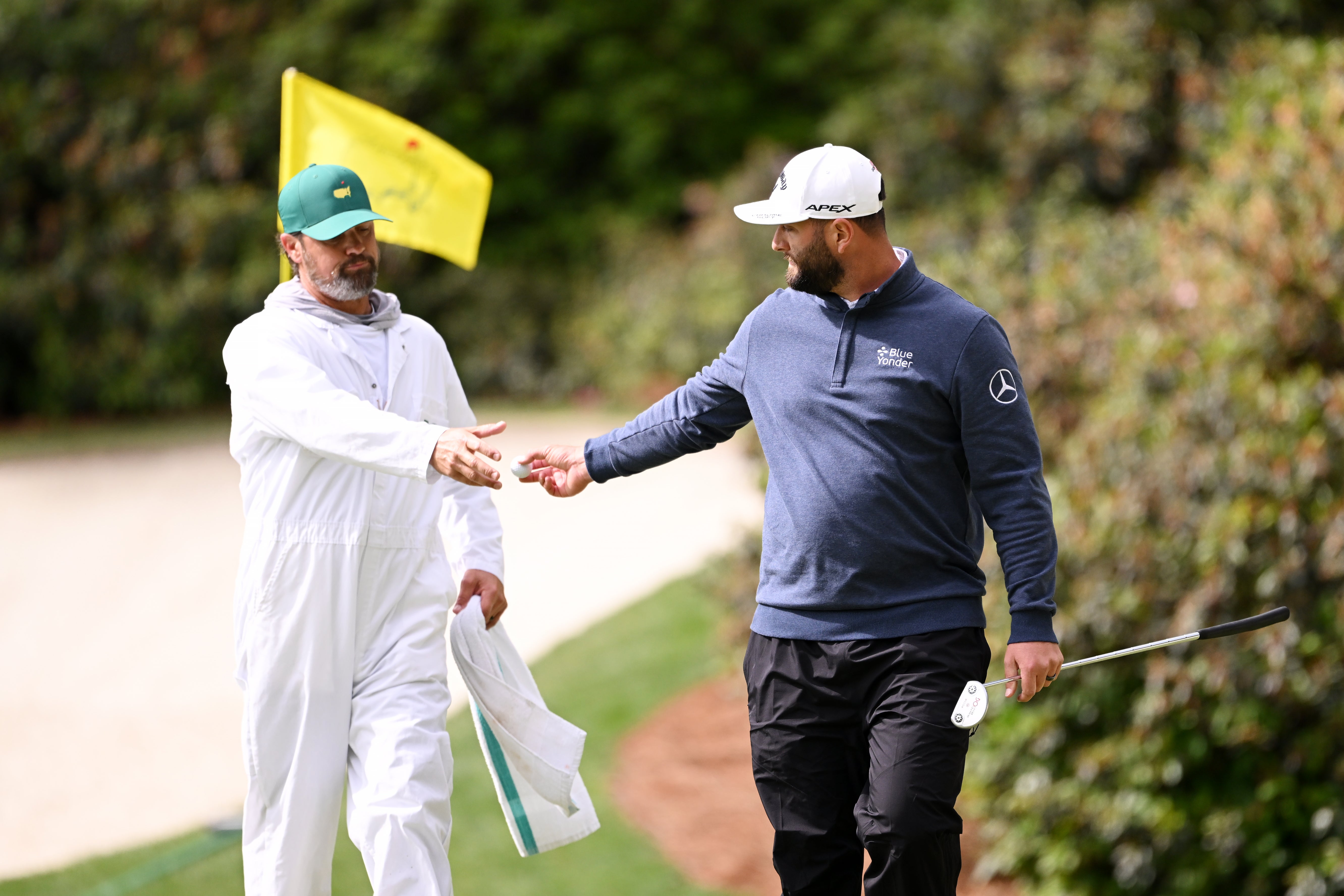 Rahm hands his ball to his caddie after making par on 13