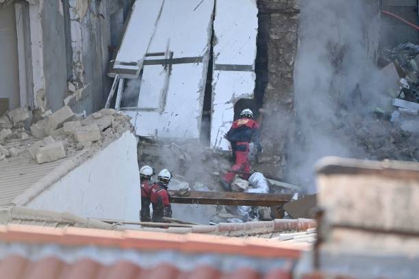 A dog handler peers into a destroyed building at ‘rue Tivoli’ after a building collapsed in the street, in Marseille, southern France, on 9 April 2023