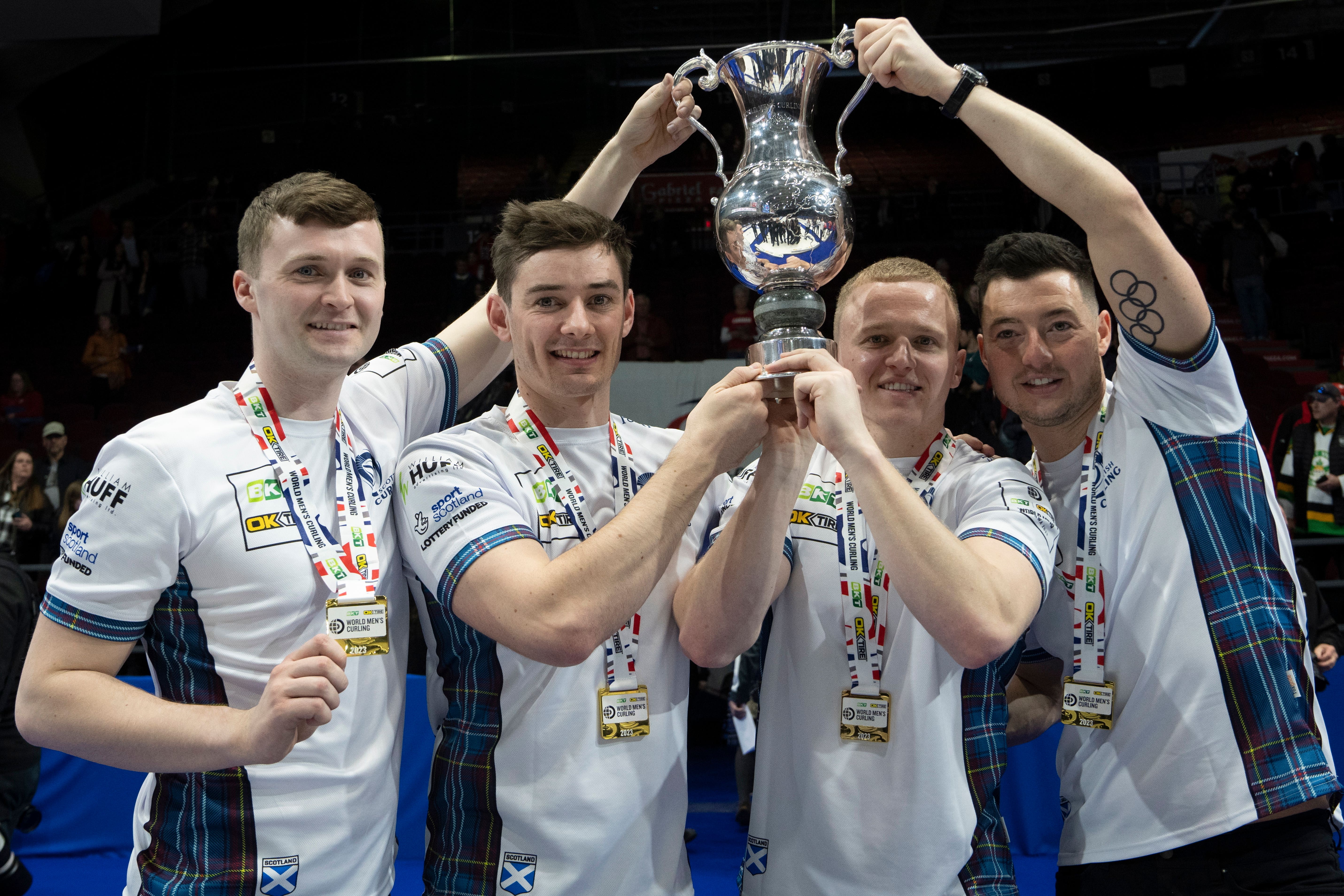 Bruce Mouat and team-mates Grant Hardie, Bobby Lammie and Hammy McMilllan, left to right, lift the World Championship trophy (Adrian Wyld /AP)