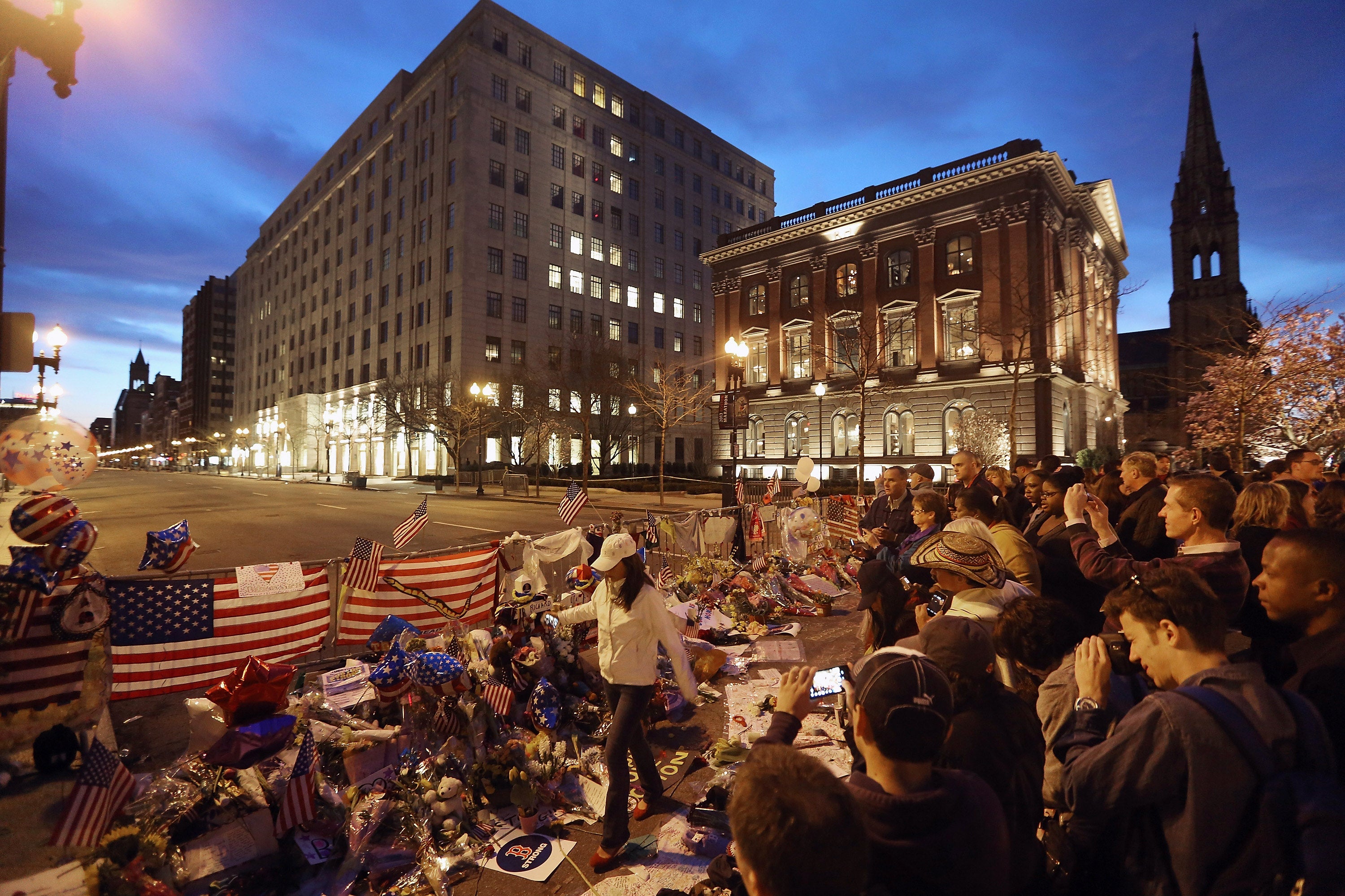 People gather at a makeshift memorial for victims near the site of the Boston Marathon bombings a day after the second suspect was captured on 20 April 2013 in Boston, Massachusetts