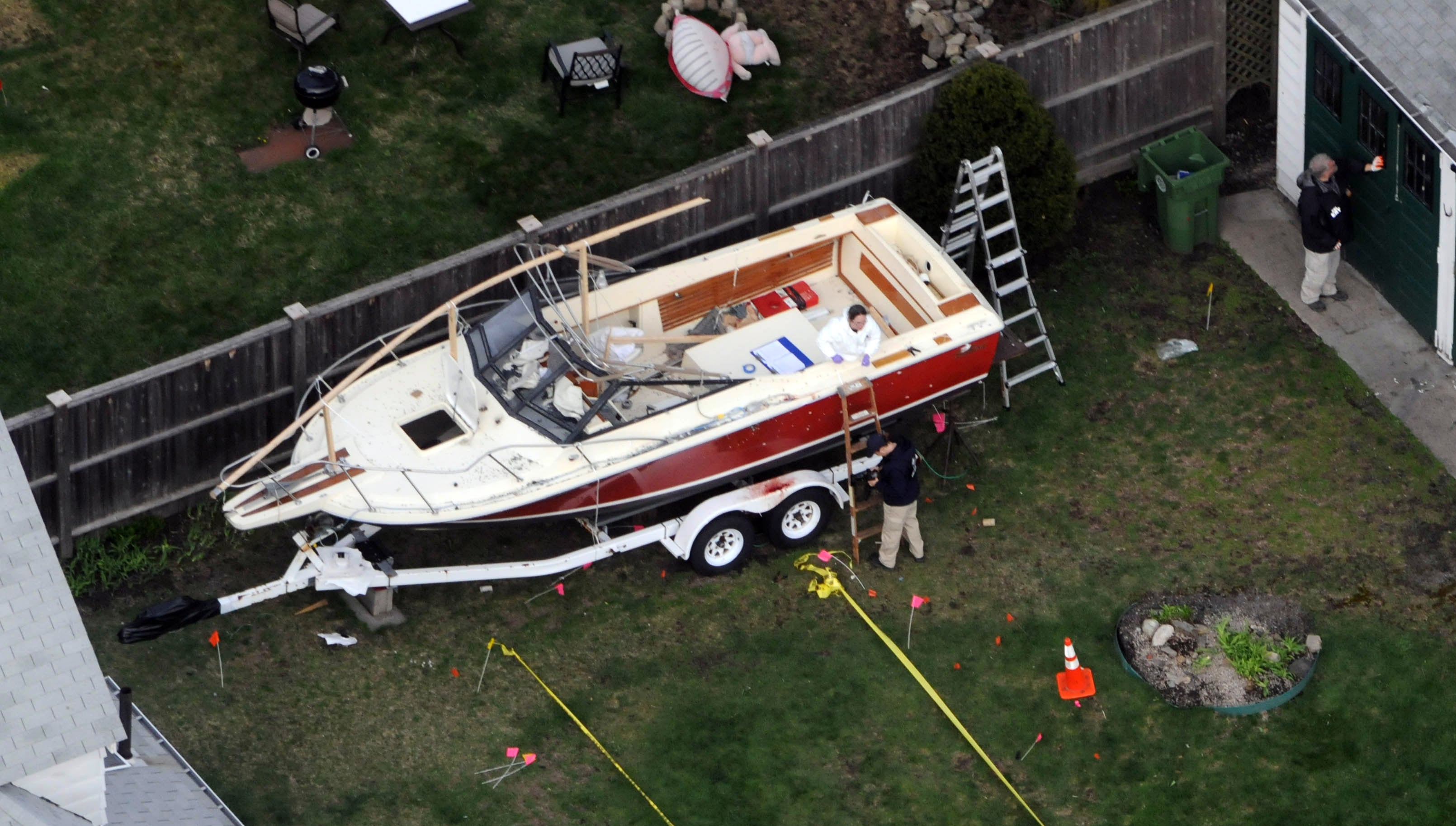 Investigators work around the boat where Dzhokhar Tsarnaev was found hiding after a massive manhunt, in the back yard of a Franklin Street home, on 20 April 2013 in Watertown, Massachusetts