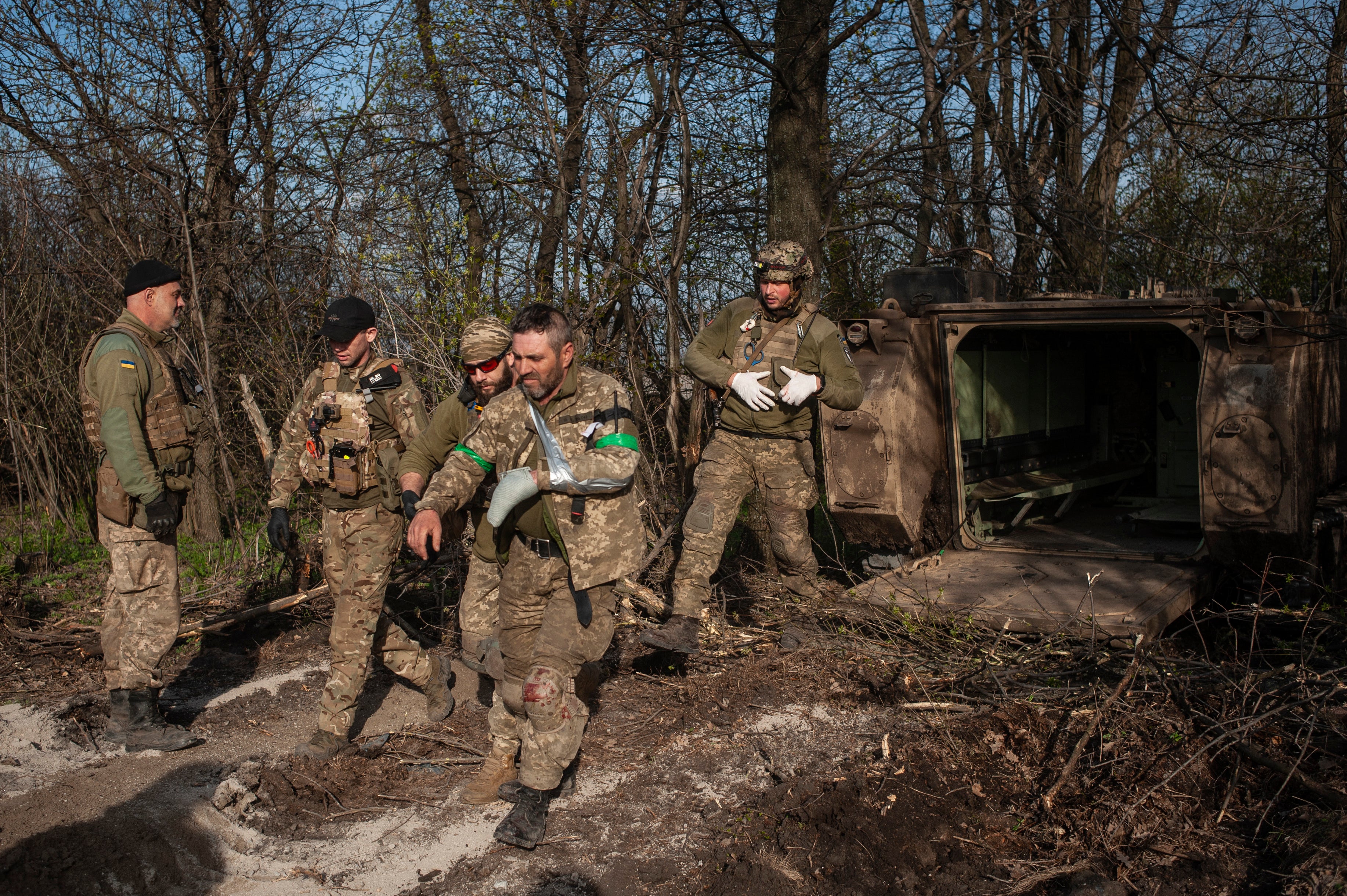 Military medics help a soldier wounded in a battle to get into an evacuation vehicle near Bakhmut, Donetsk region, Ukraine, Monday, 10 April 2023