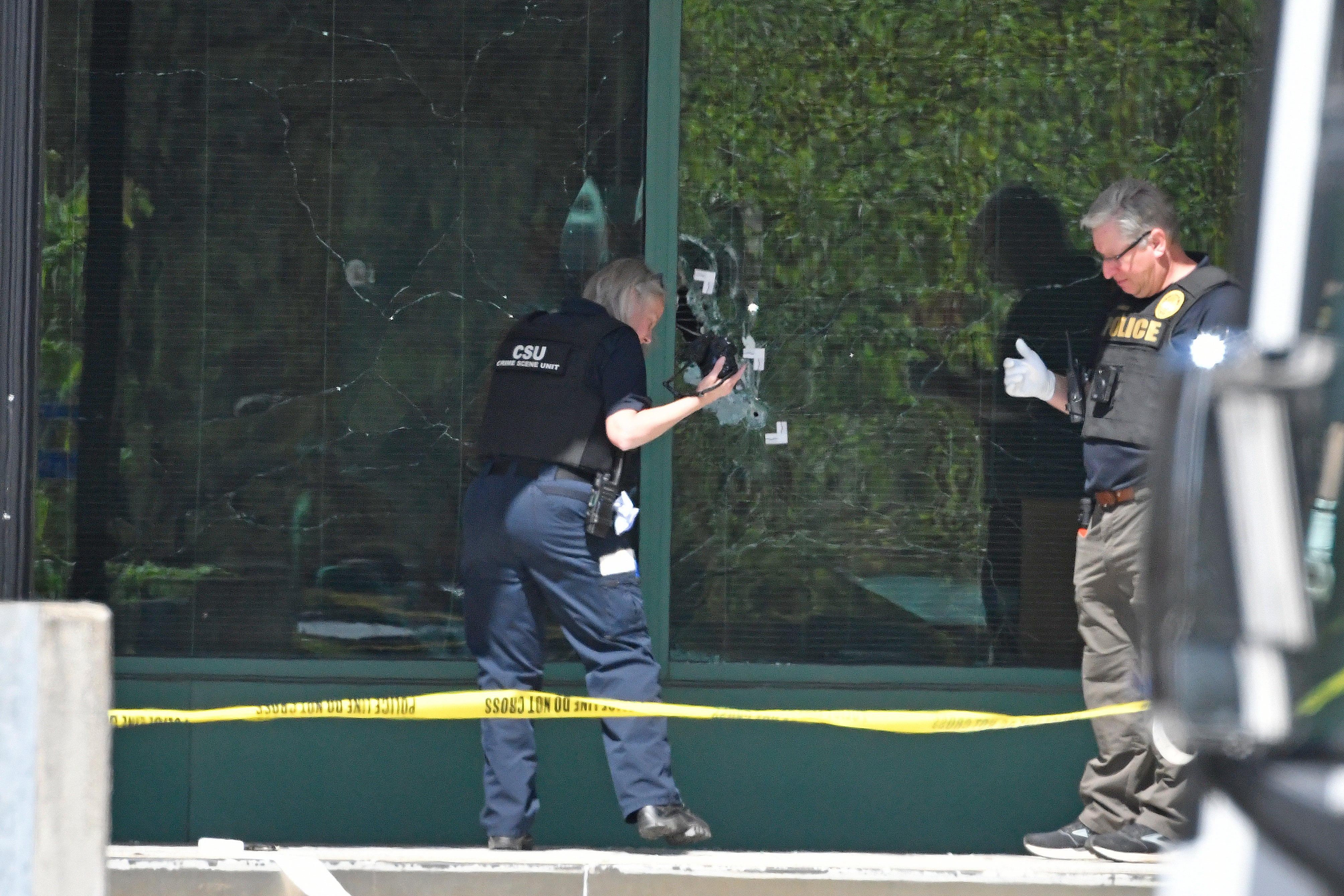 A Louisville Metro Police technician photographs bullet holes in the front glass of the Old National Bank building