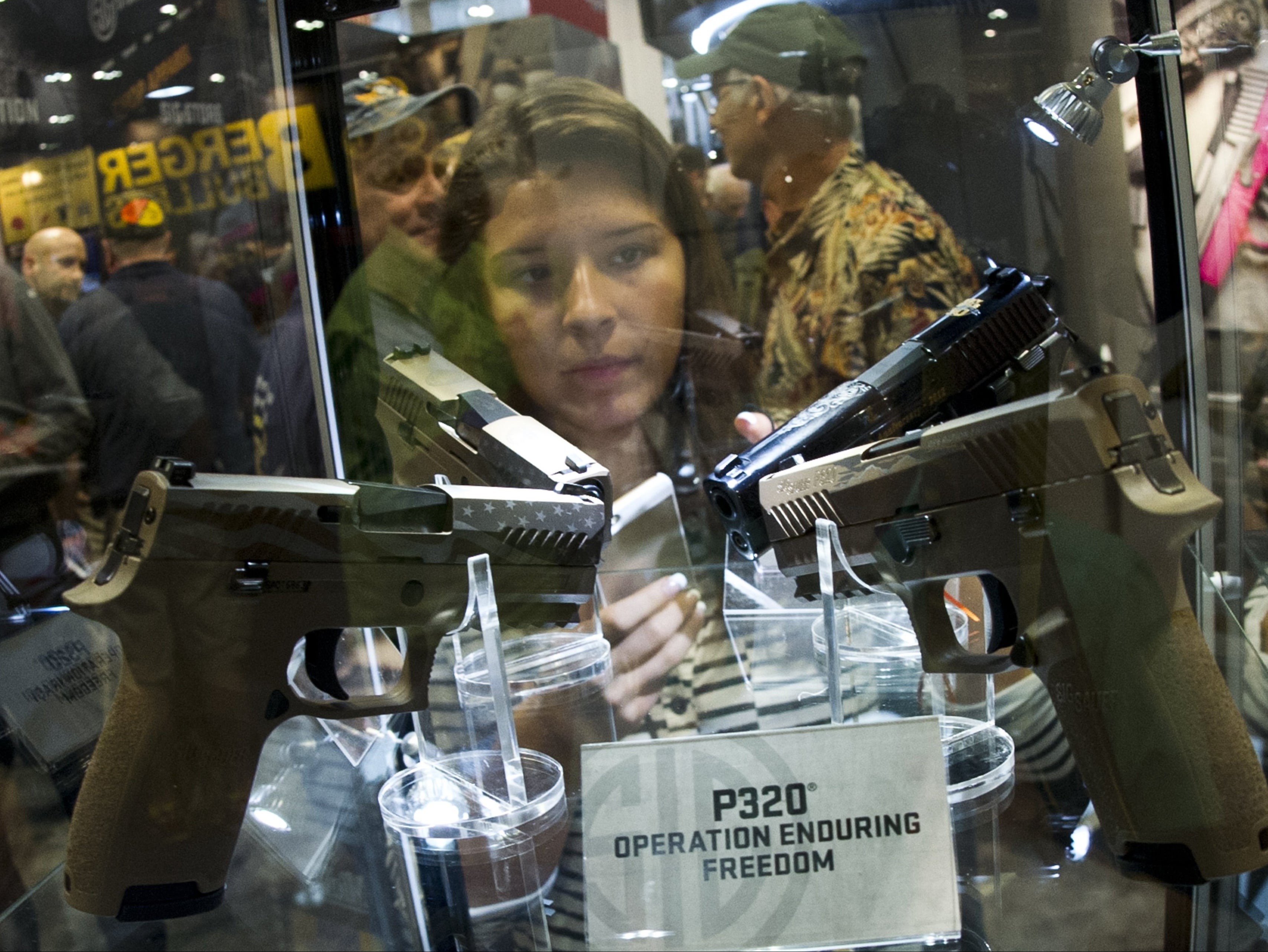 A prospective customer examines a case of Sig Sauer P320 handguns at the 2015 NRA Annual Convention in Nashville, Tennessee, not long after the model first went on sale to the public