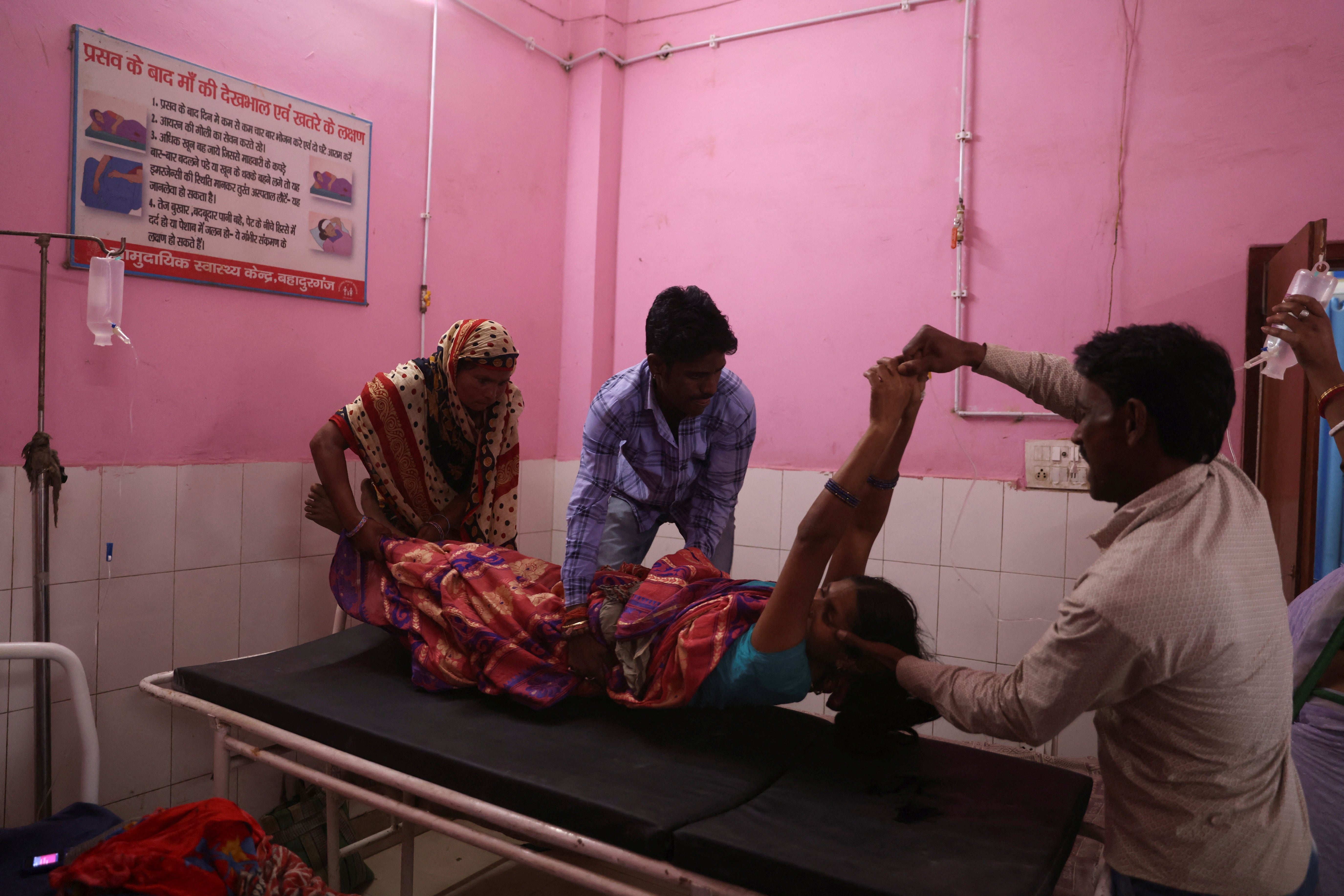 Nisha is lifted onto a hospital bed after undergoing sterilisation surgery on the same day as giving birth