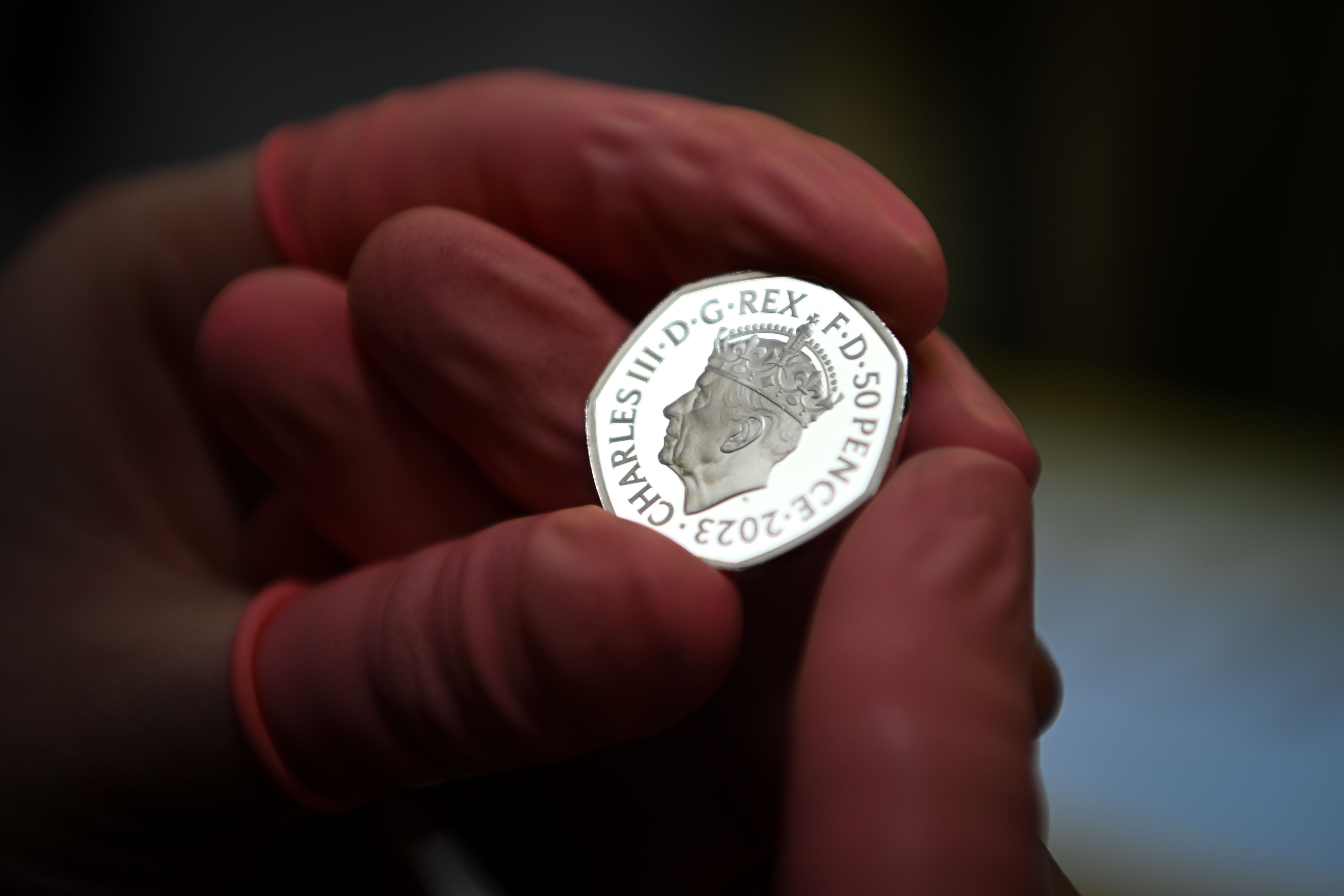 A commemorative 50 pence coin is checked for flaws after striking at The Royal Mint