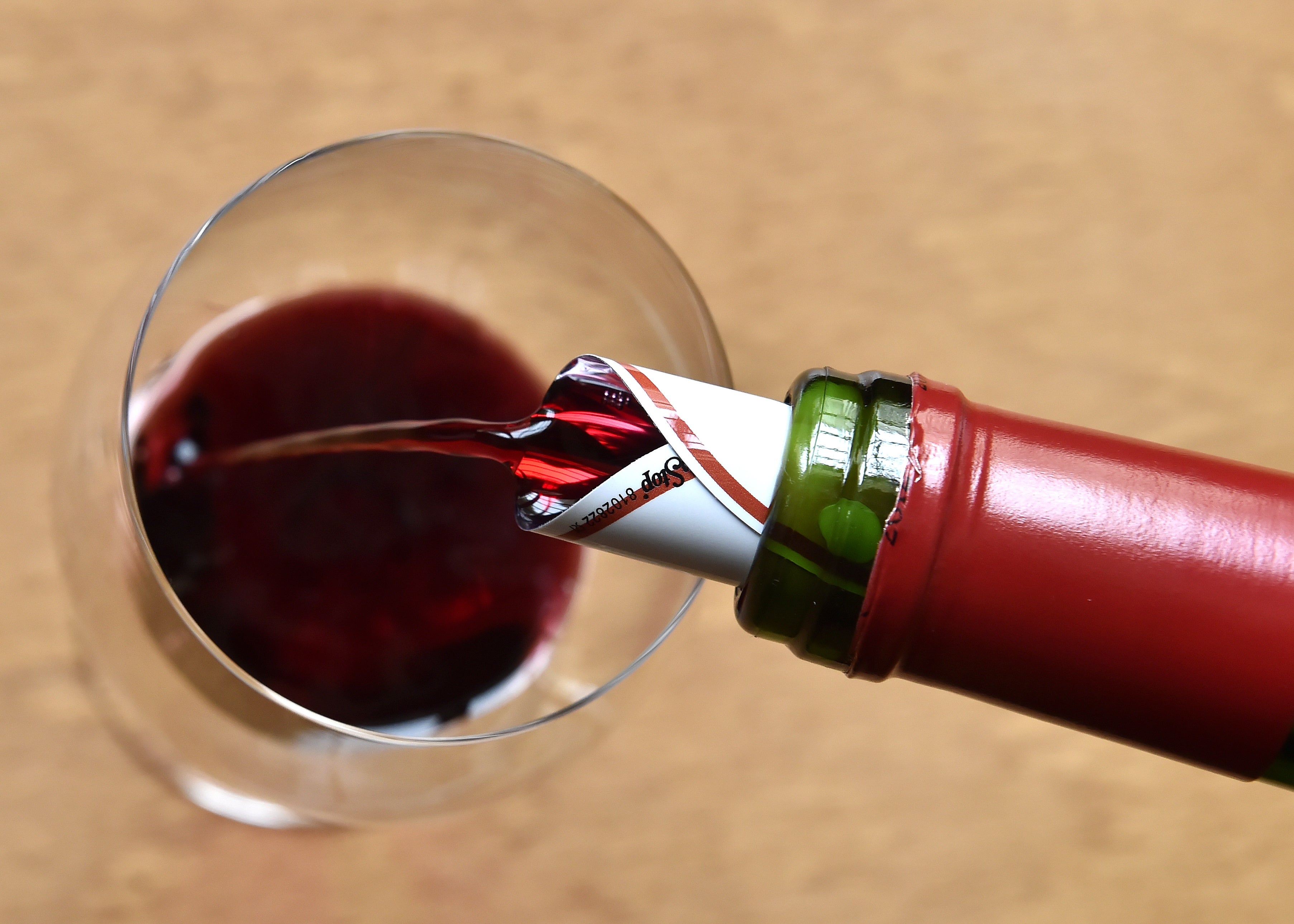 File: Red wine is served in a glass during a wine tasting session at the Etablissements Jean-Pierre Moueix wine merchant in Libourne