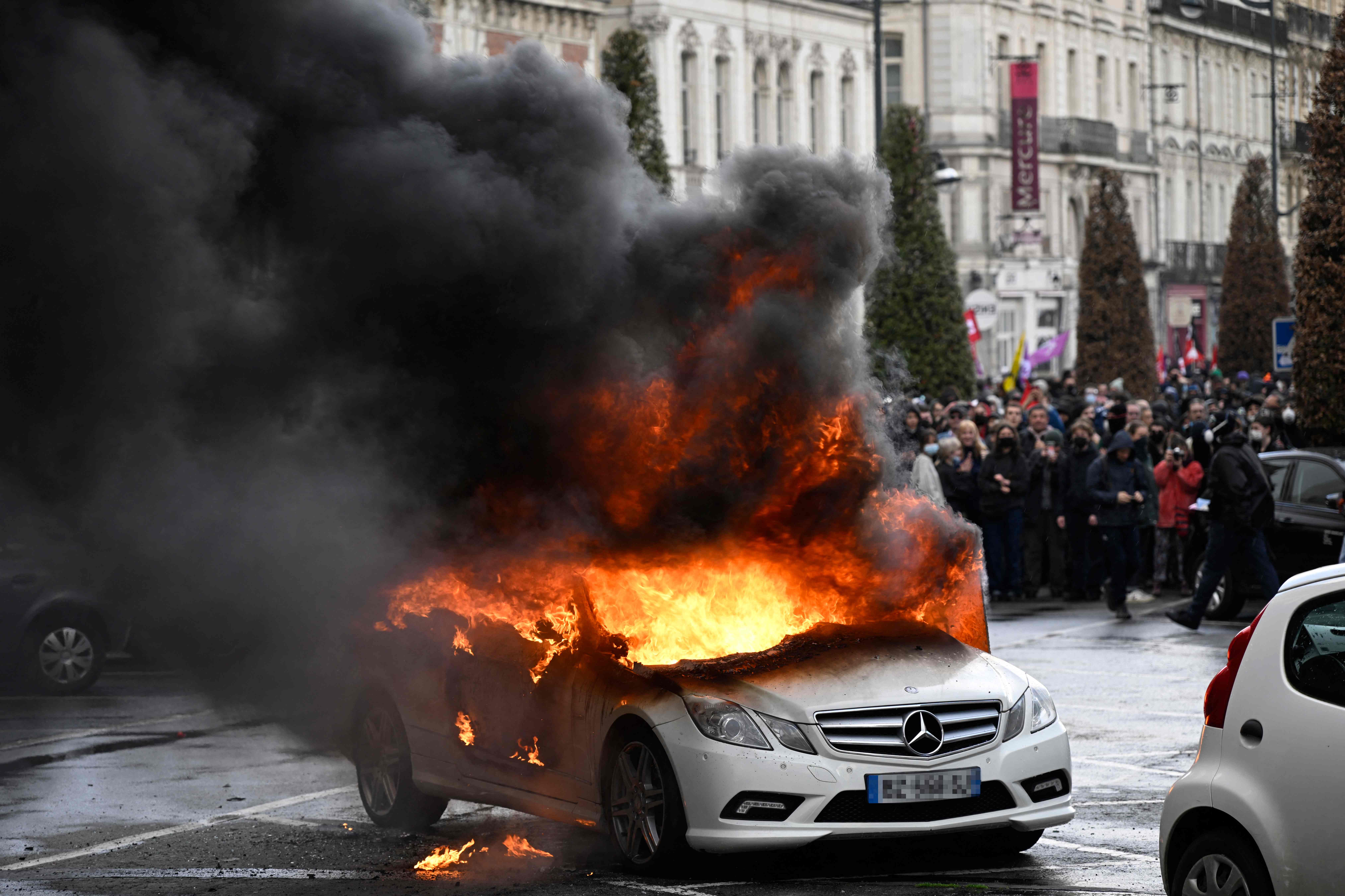 Flames rise from a Mercedes car set on fire during a demonstration on the 12th day of action after the government pushed a pensions reform through parliament without a vote, using the article 49.3 of the constitution, in Rennes, northwestern France