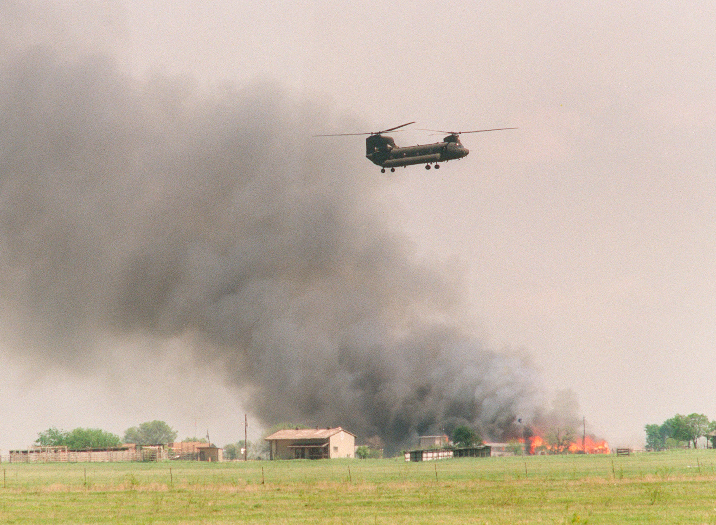 A National Guard helicopter flies past the burning Branch Davidian cult compound on 19 April 1993