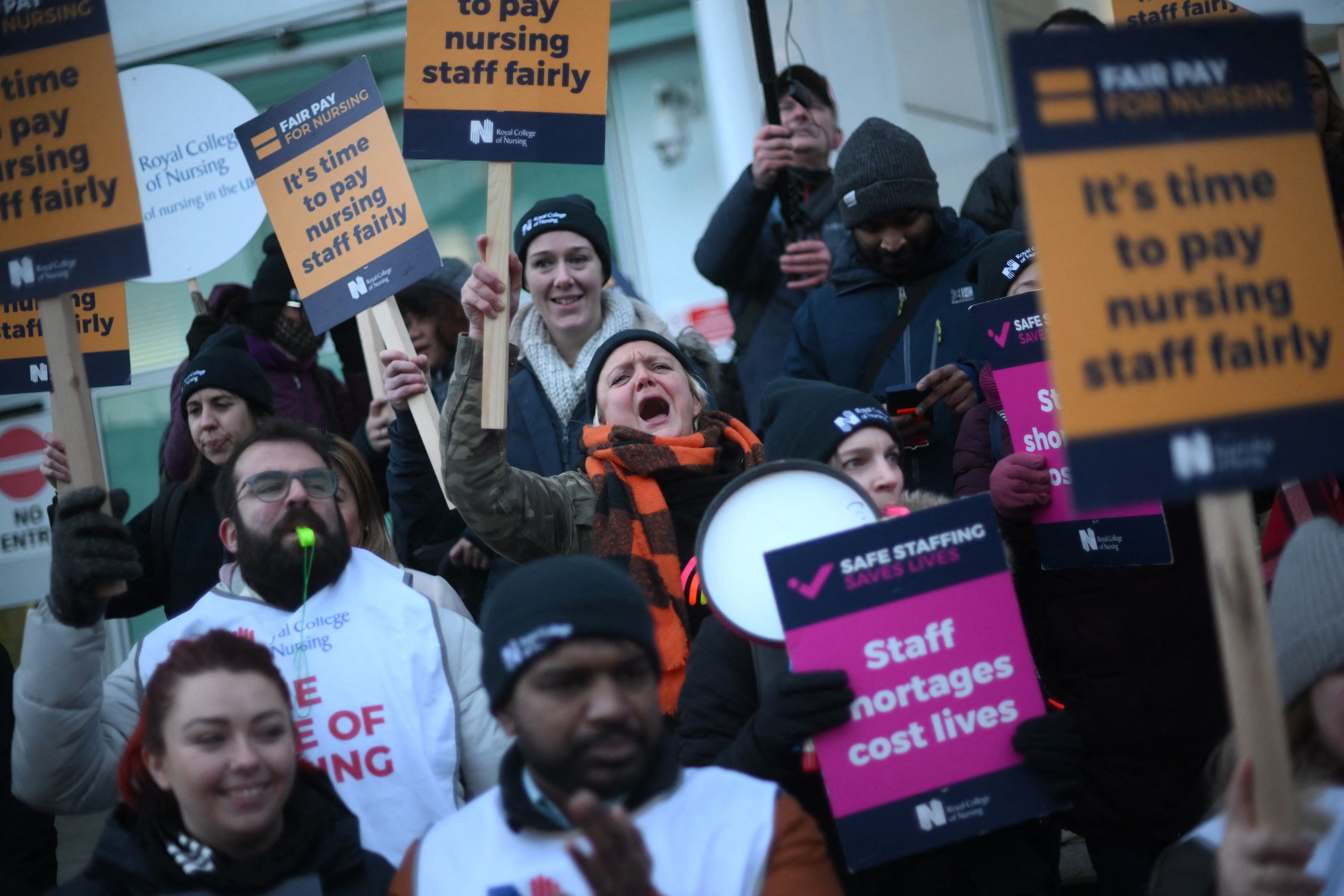 Striking nurses hold signs at a picket line outside University College Hospital in London