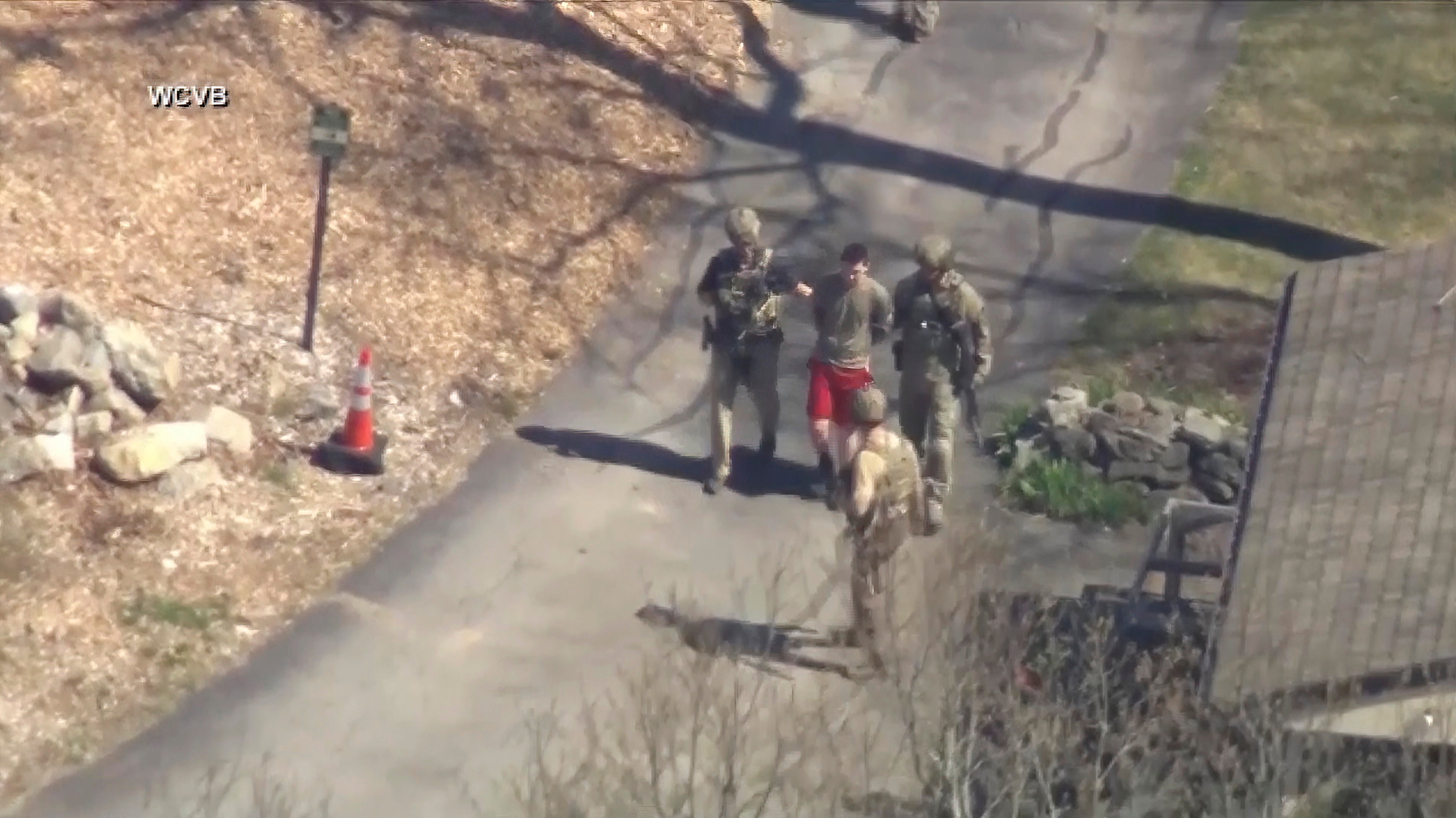 Jack Teixeira, in t-shirt and shorts, being taken into custody by armed tactical agents on Thursday, in Dighton, Massachusetts