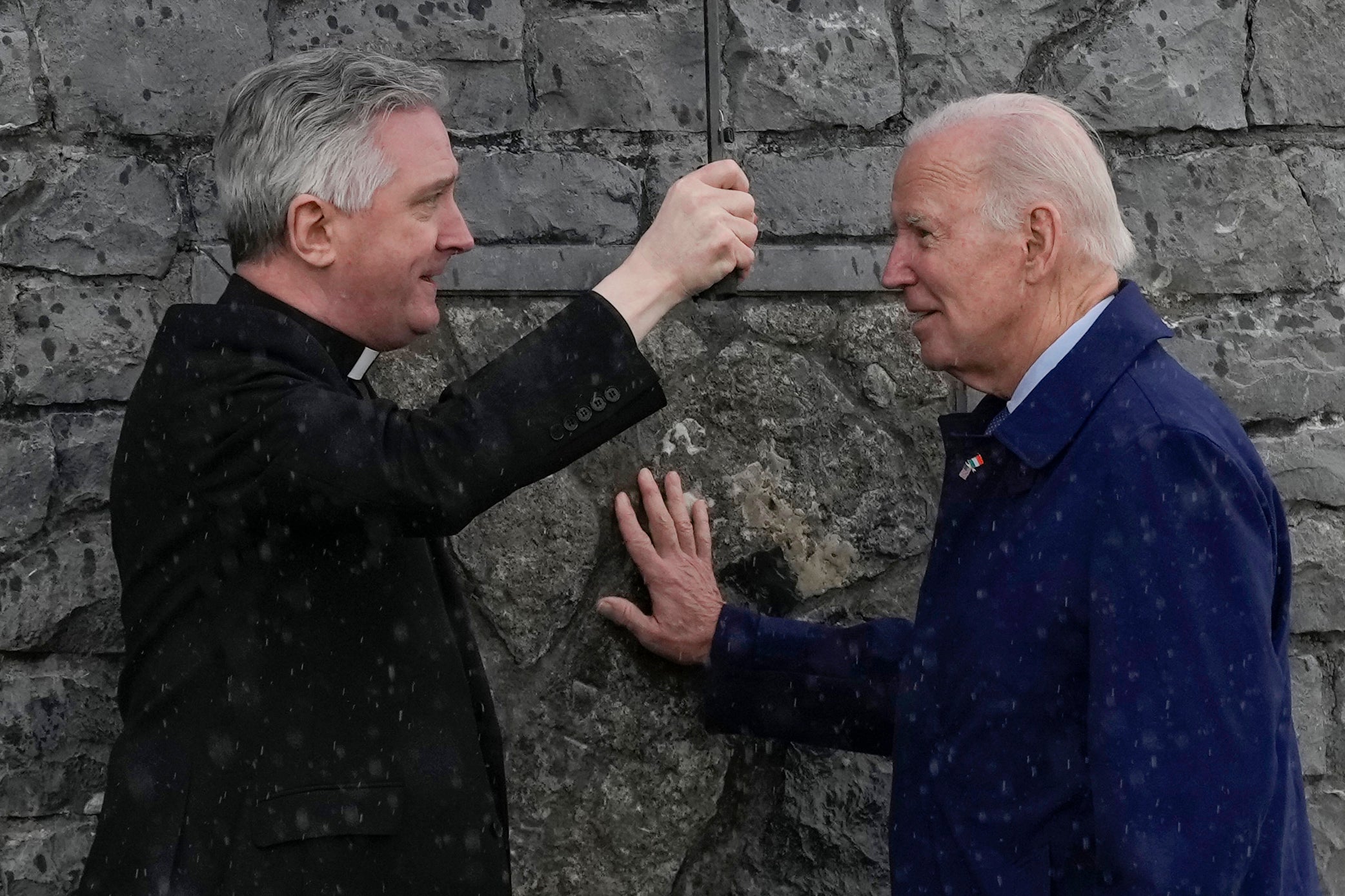 Mr Biden touches part of the original stonework from the apparition gable at the Knock Shrine as he talks with Father Richard Gibbons