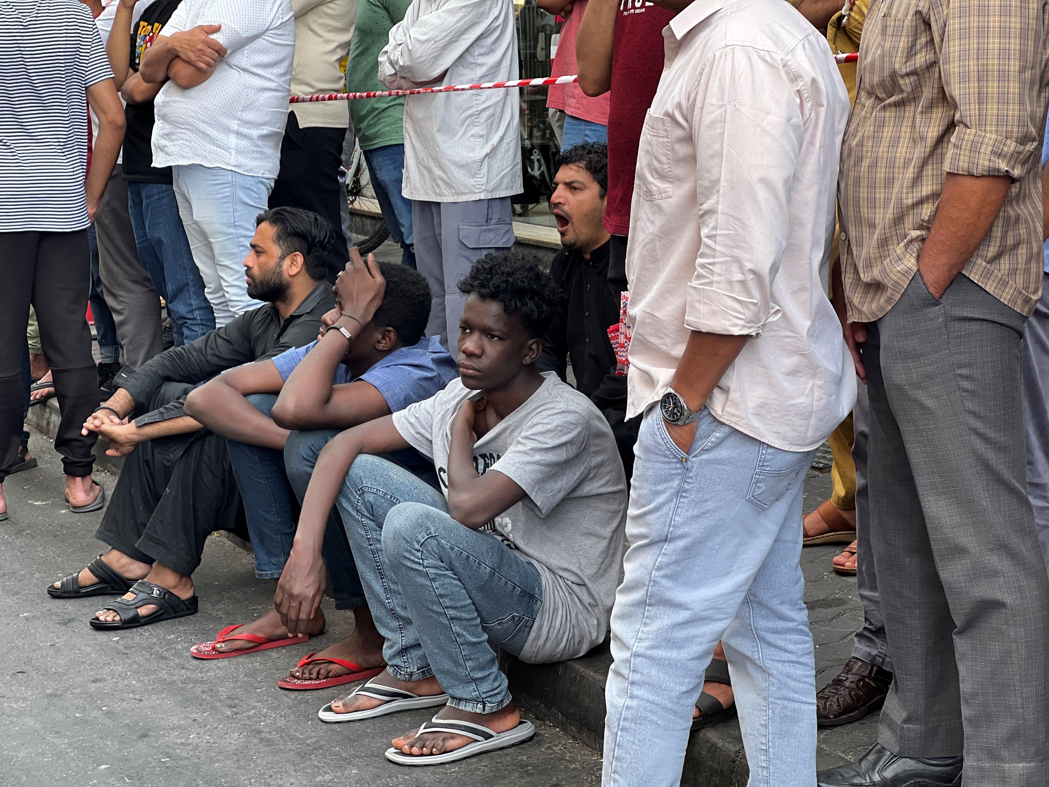 People, including residents, stand outside a residential building that was devastated by a fire where several people were killed and others injured in Dubai, United Arab Emirates