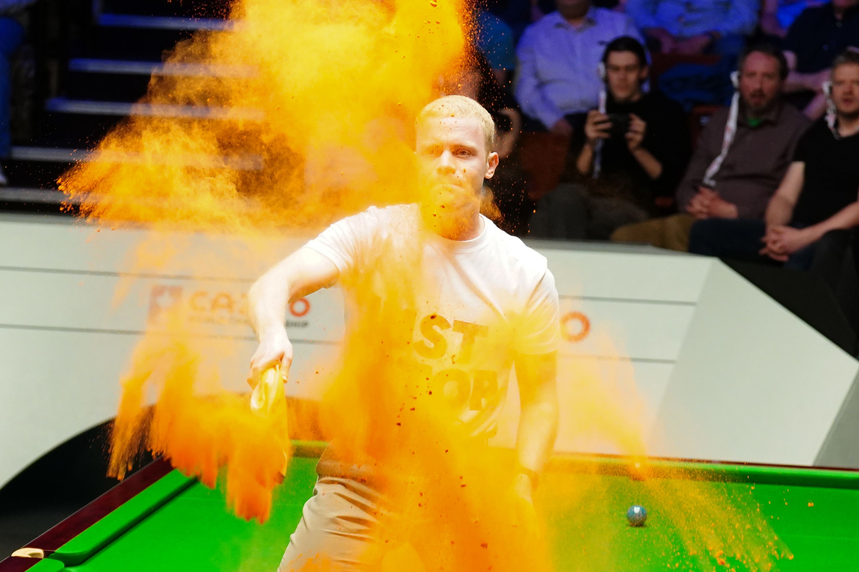 A Just Stop Oil protester jumps on the table and throws orange powder (Mike Egerton/PA)