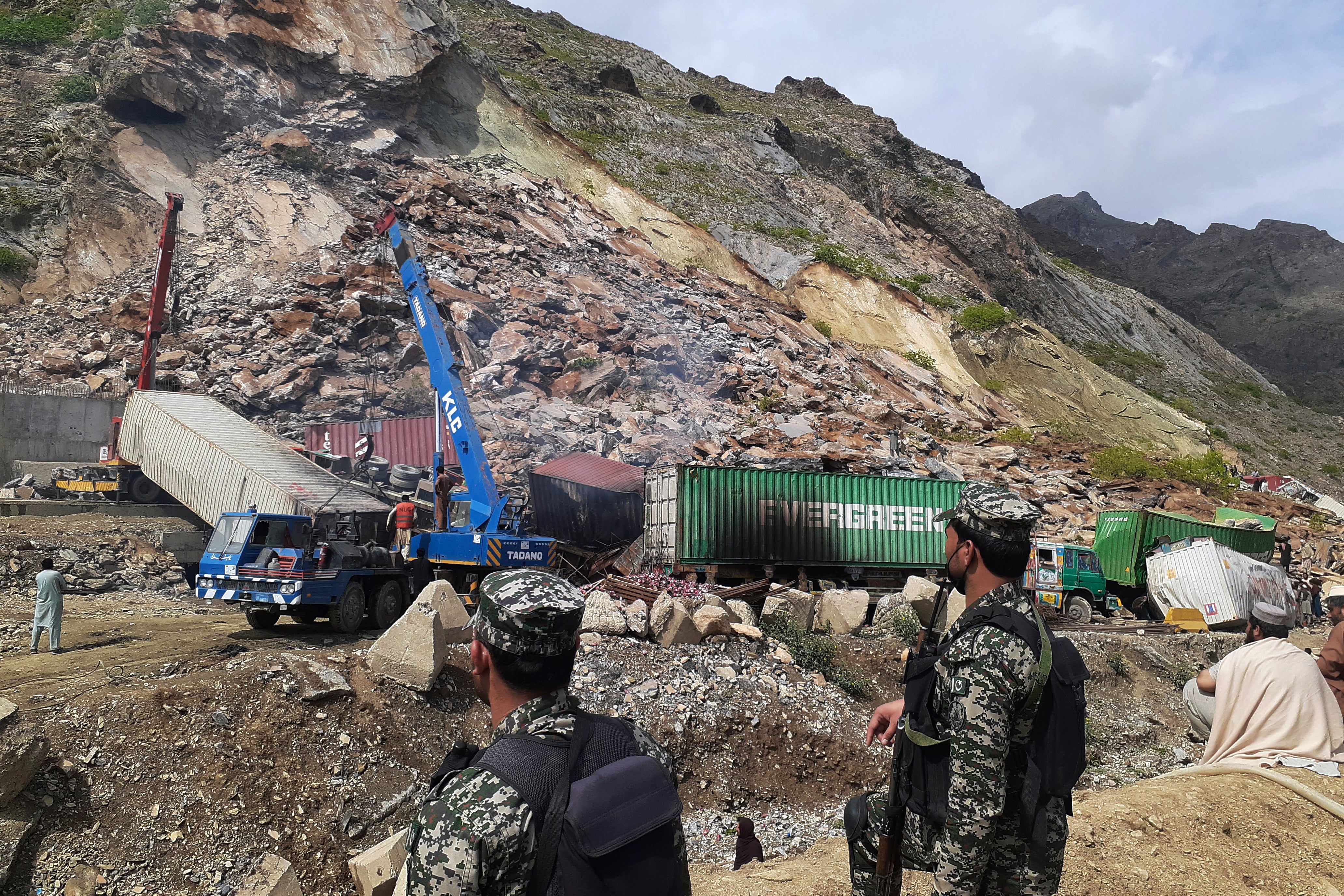 Paramilitary soldiers stand guard as authorities use heavy machines to search survivors and clear the rubble following a landslide in northwestern Pakistan on Tuesday