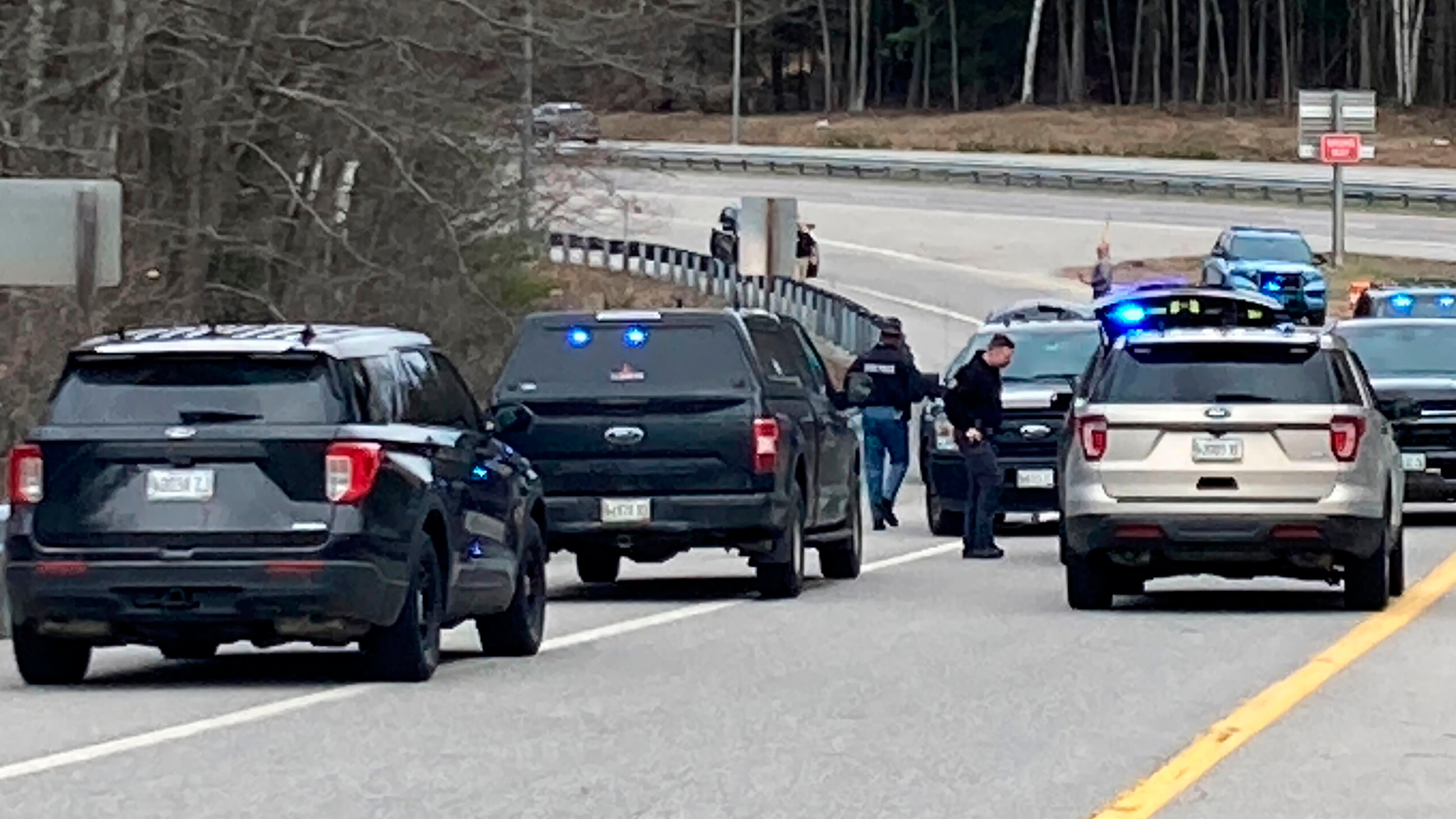 Members of law enforcement approach vehicles at a scene where people were injured in a shooting on Interstate 295 in Yarmouth, Maine