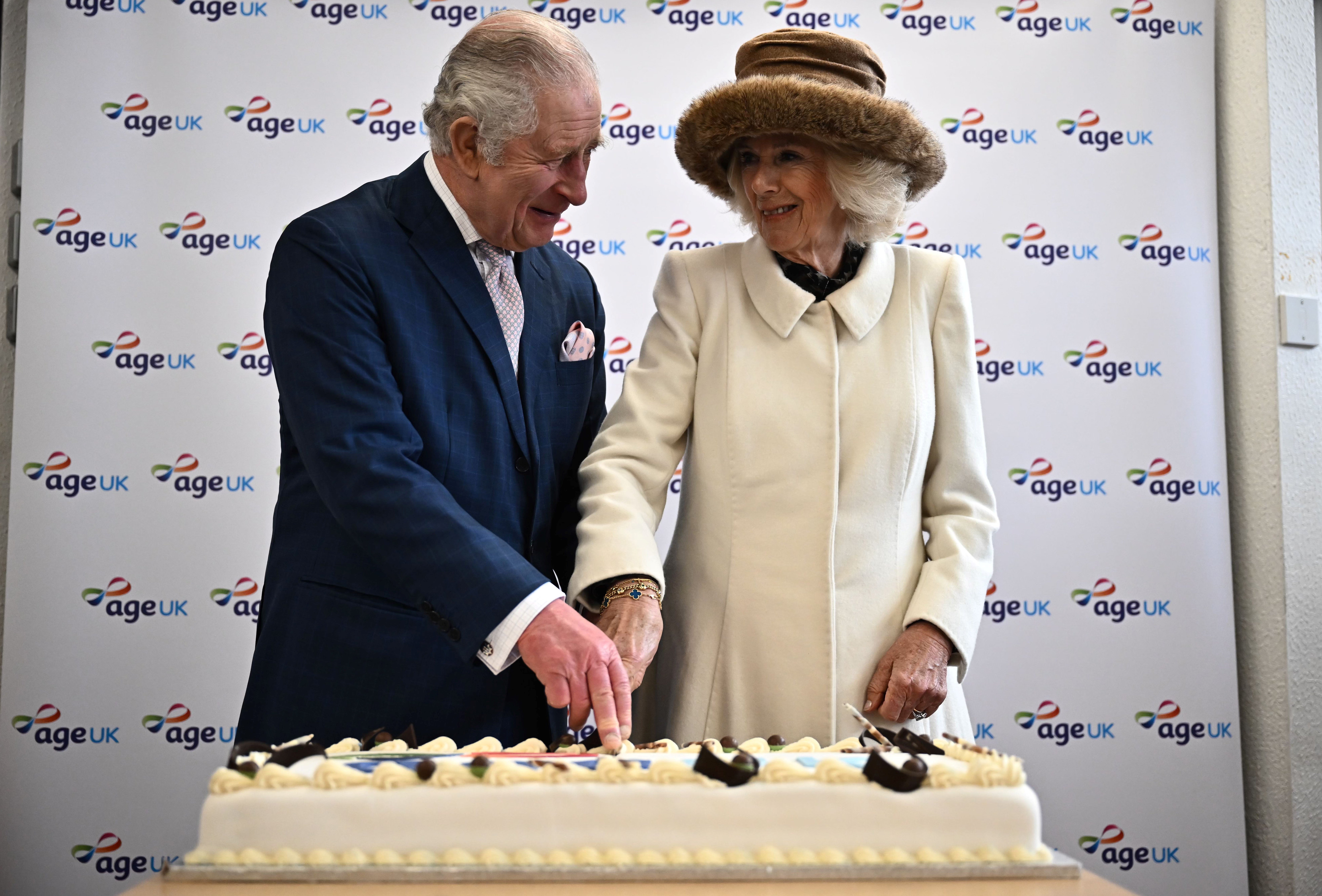 King Charles III (L) and Camilla, Queen Consort (R) cut a cake during an afternoon tea with volunteers and service users of the charity organisation Age UK at the Colchester Library during a visit to Colchester on March 7, 2023