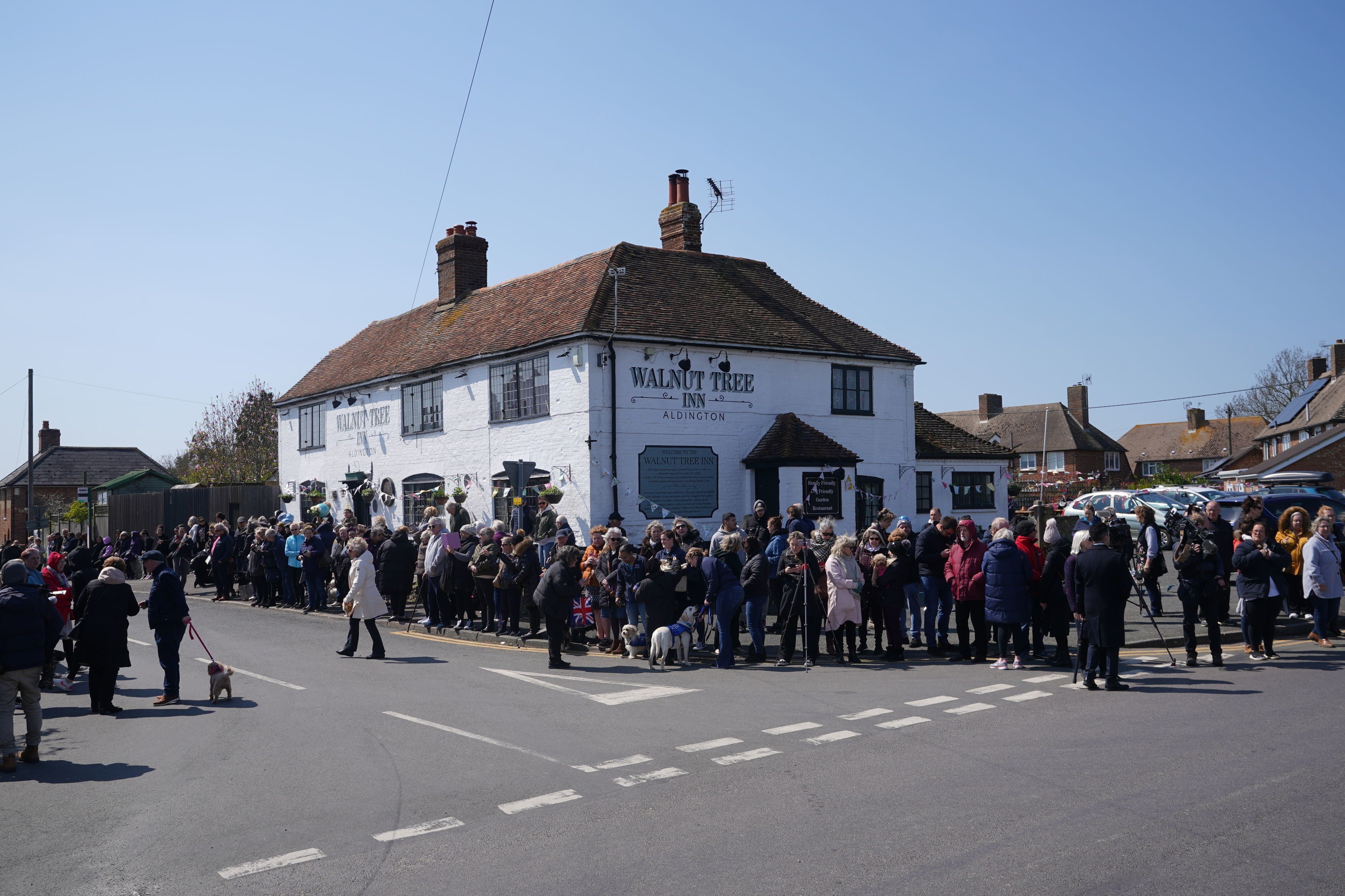 Mourners gather outside the Walnut Tree Pub in Aldington