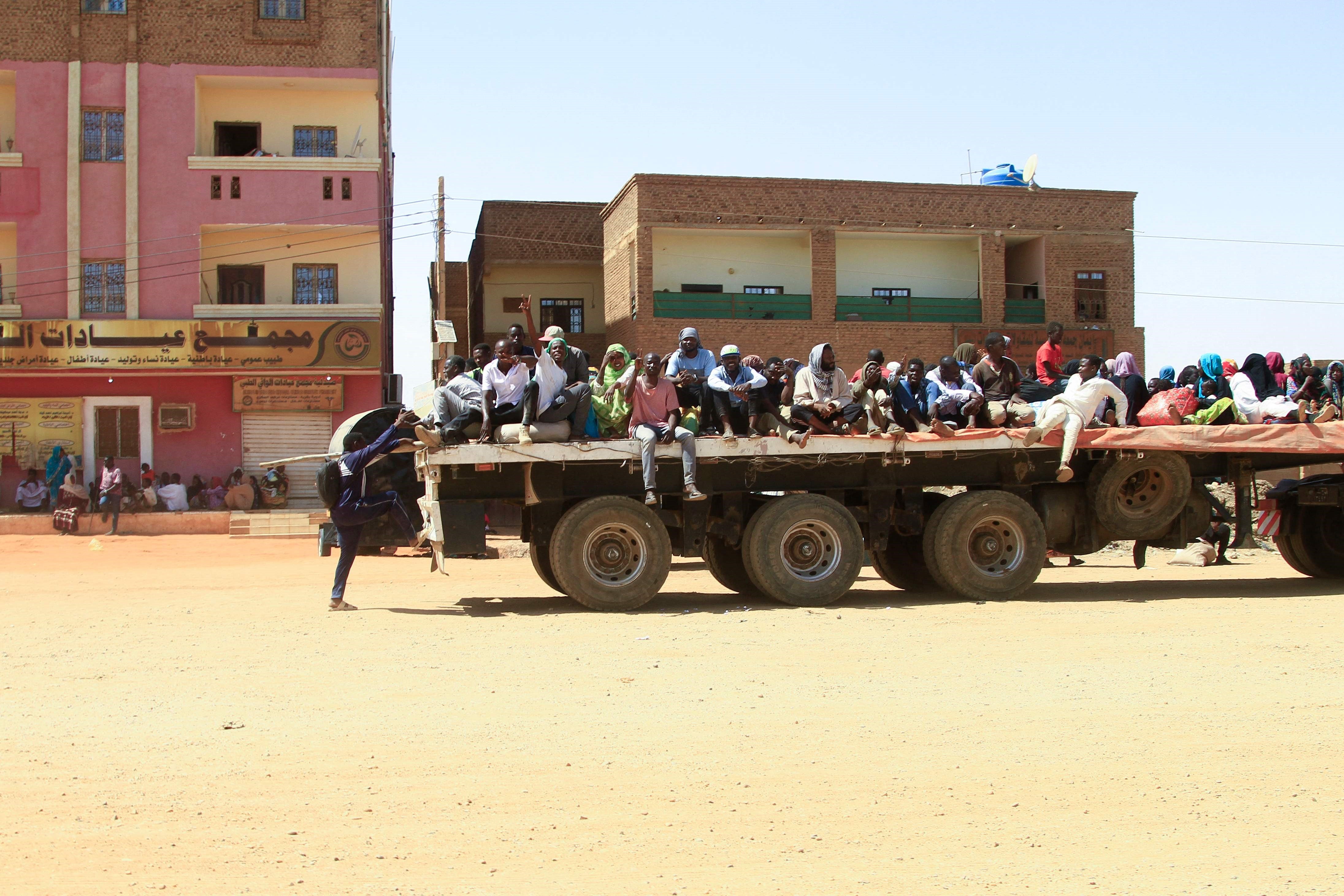 People fleeing street battles are transported on the back of a truck in the southern part of Khartoum