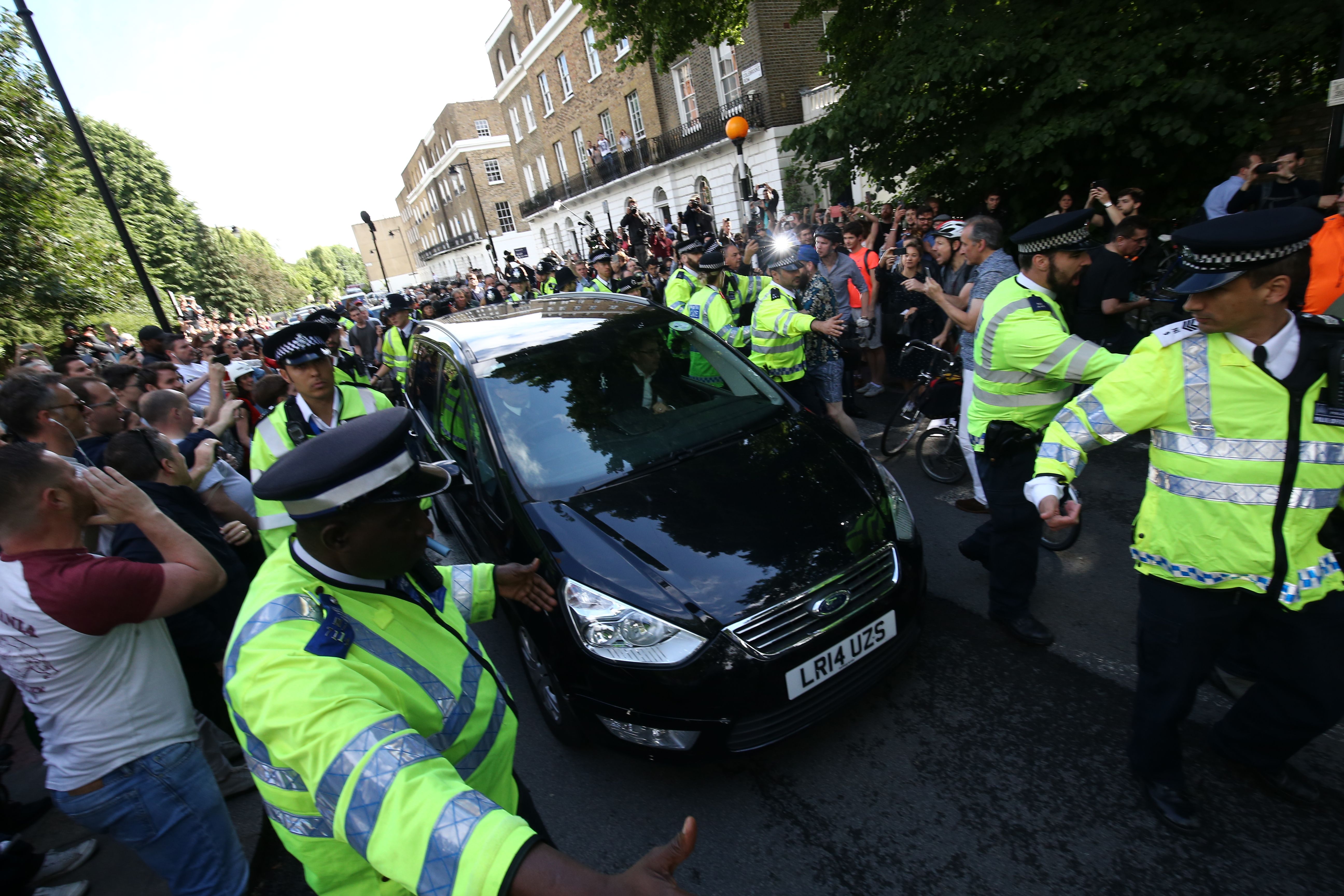 Police escort Johnson’s car through protesters away from his home