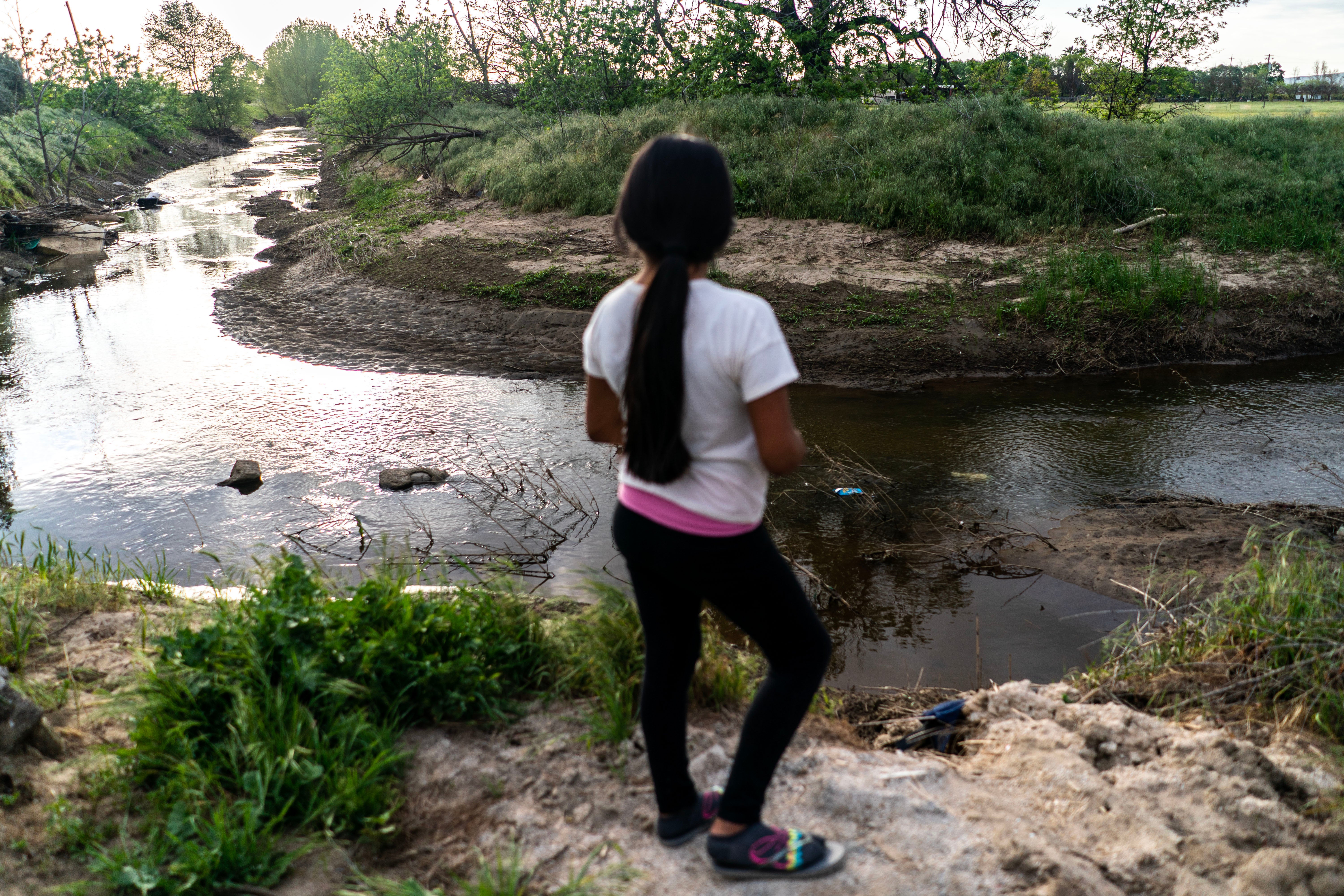 A girl stands on the bank of a stream in Cutler, California, that overflowed during relentless rain