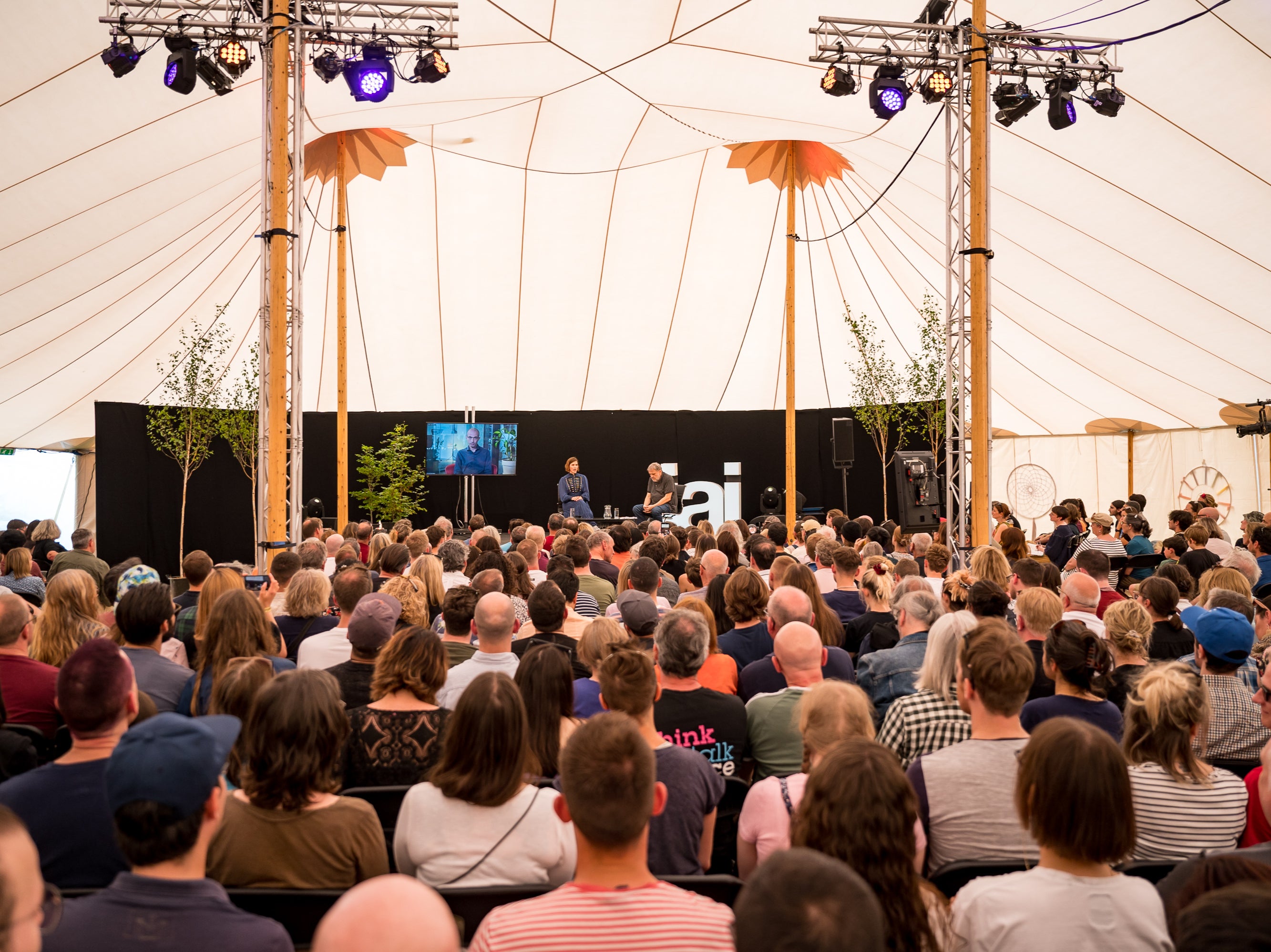 A crowd gathers under a tent at HowTheLightGetsIn Festival