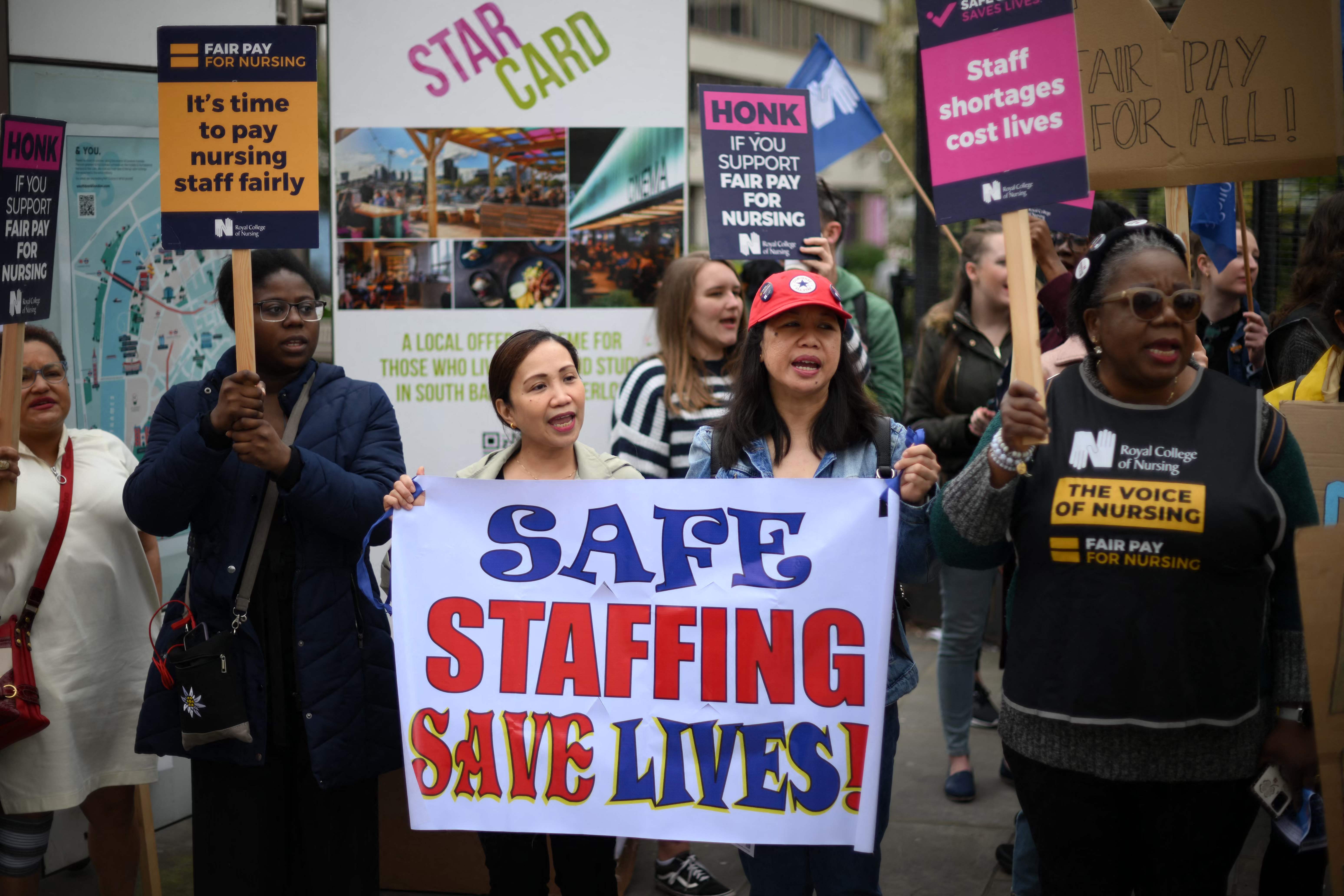 Healthcare workers hold placards as they demonstrate outside St Thomas' Hospital in London