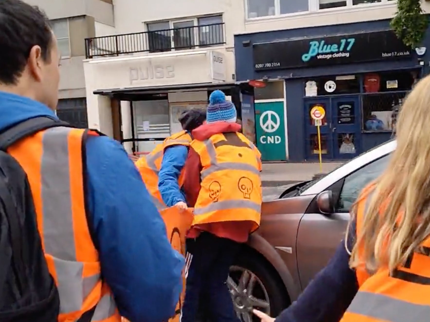 A protestor attempts to block the car as it makes its way down the road