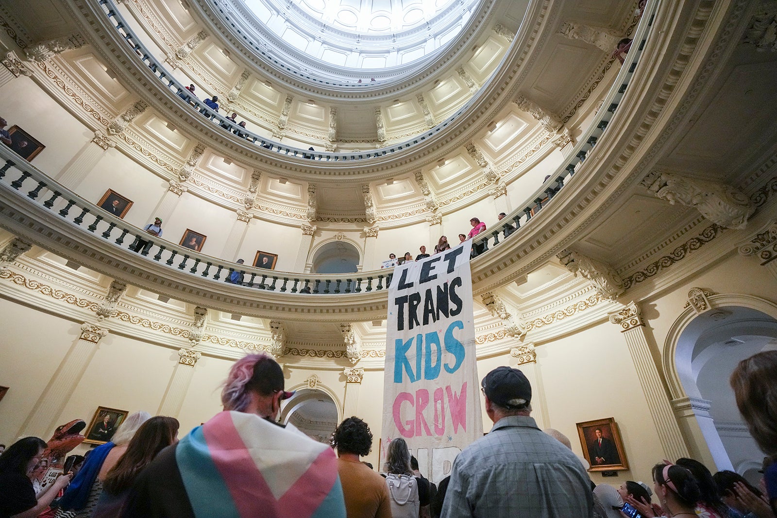 Equality Texas leadership drops a banner in the Capitol rotunda reading "let trans kids grow up"