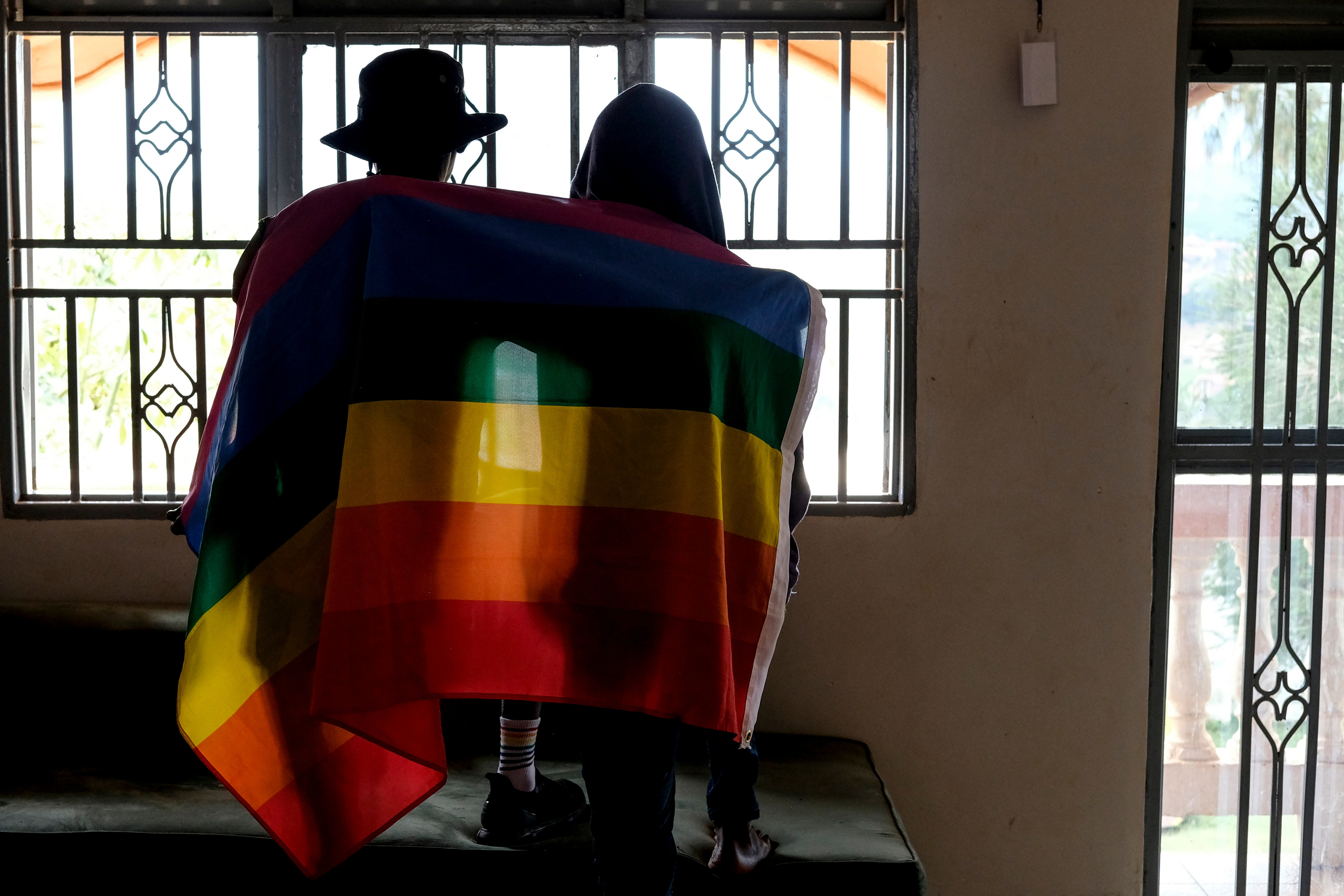 A gay Ugandan couple cover themselves with a pride flag in Uganda