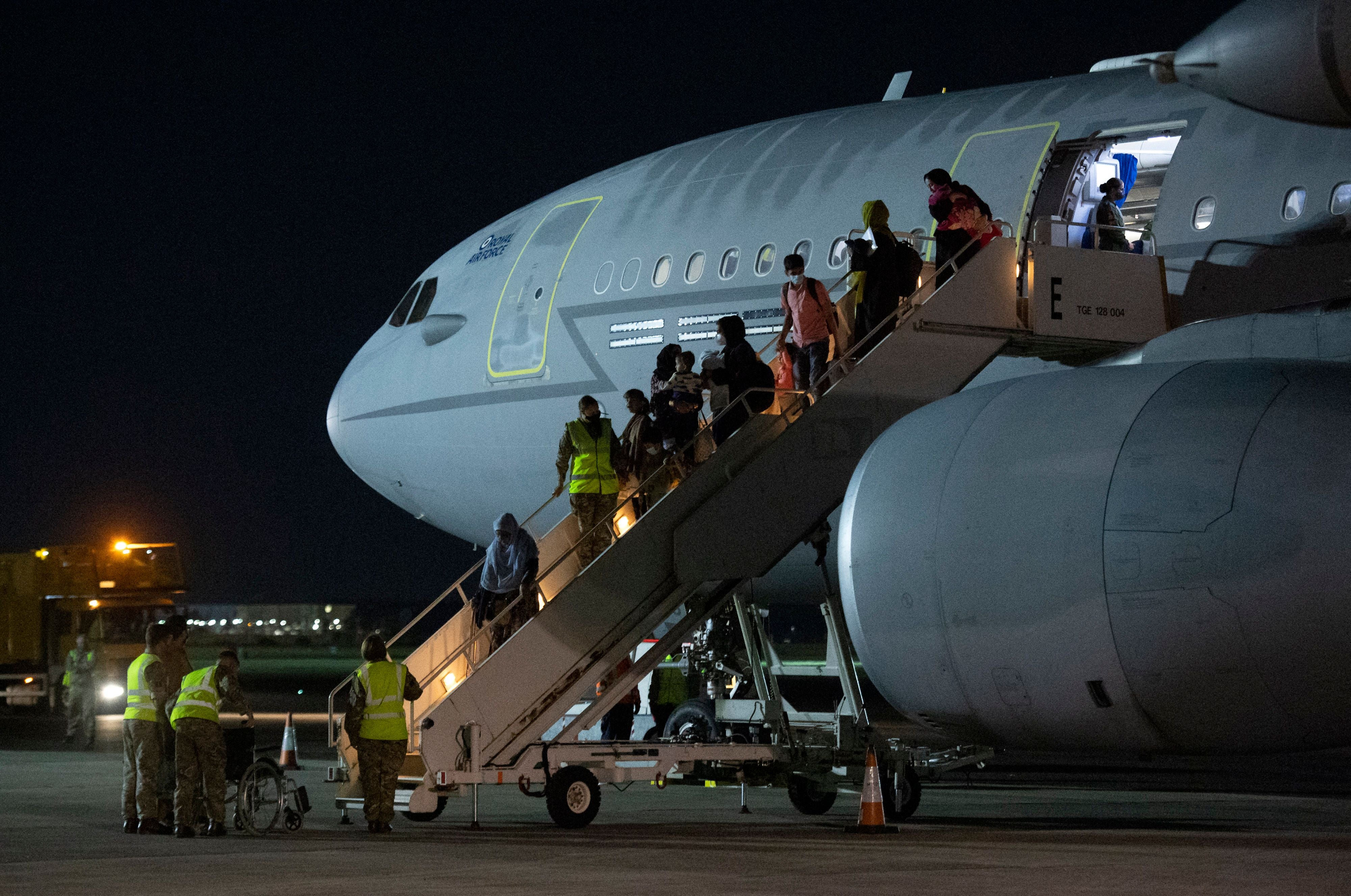 Passengers evacuated from Afghanistan disembark from a British Royal Air Force aircraft after landing in southern England on 24 August 2021