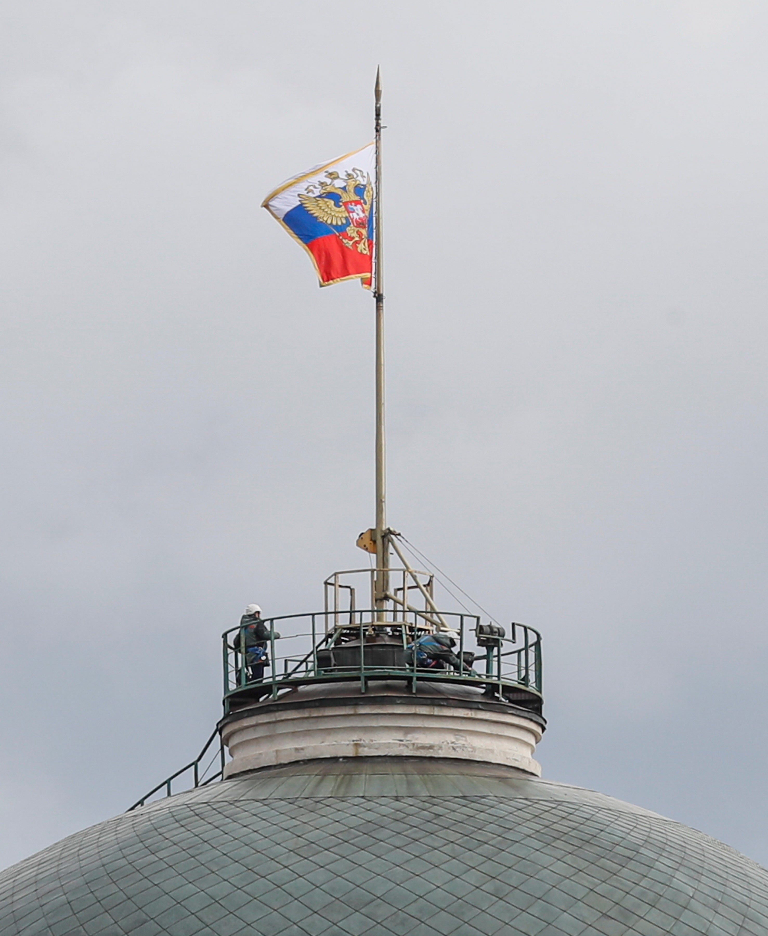 Men work on the roof near the national flag of Russia above the residence of Russian President Vladimir Putin
