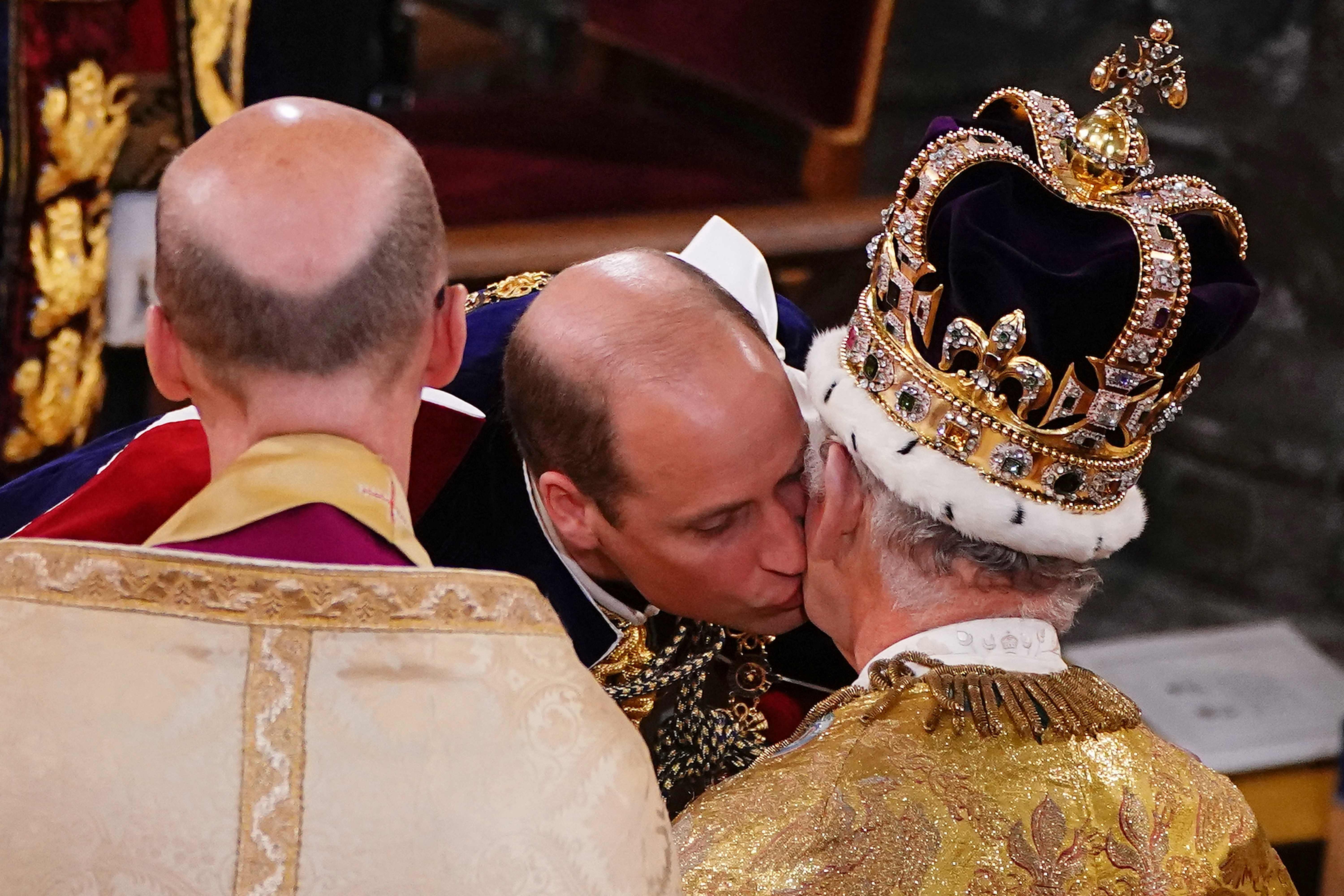 Britain's Prince William, Prince of Wales kisses his father, Britain's King Charles III, wearing St Edward's Crown, during the King's Coronation Ceremony