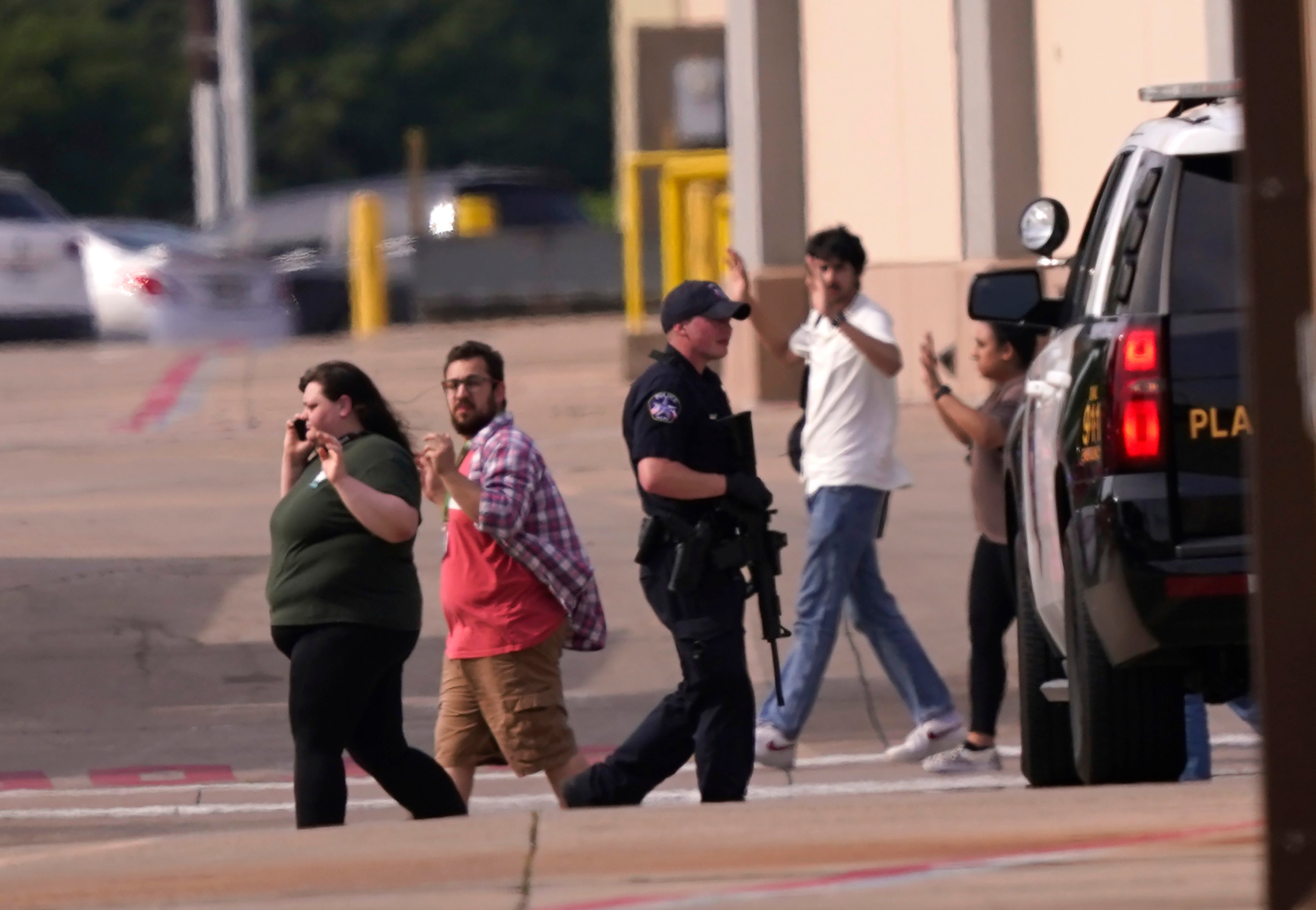 Survivors leave the scene of a mass shooting at a mall in Allen, Texas