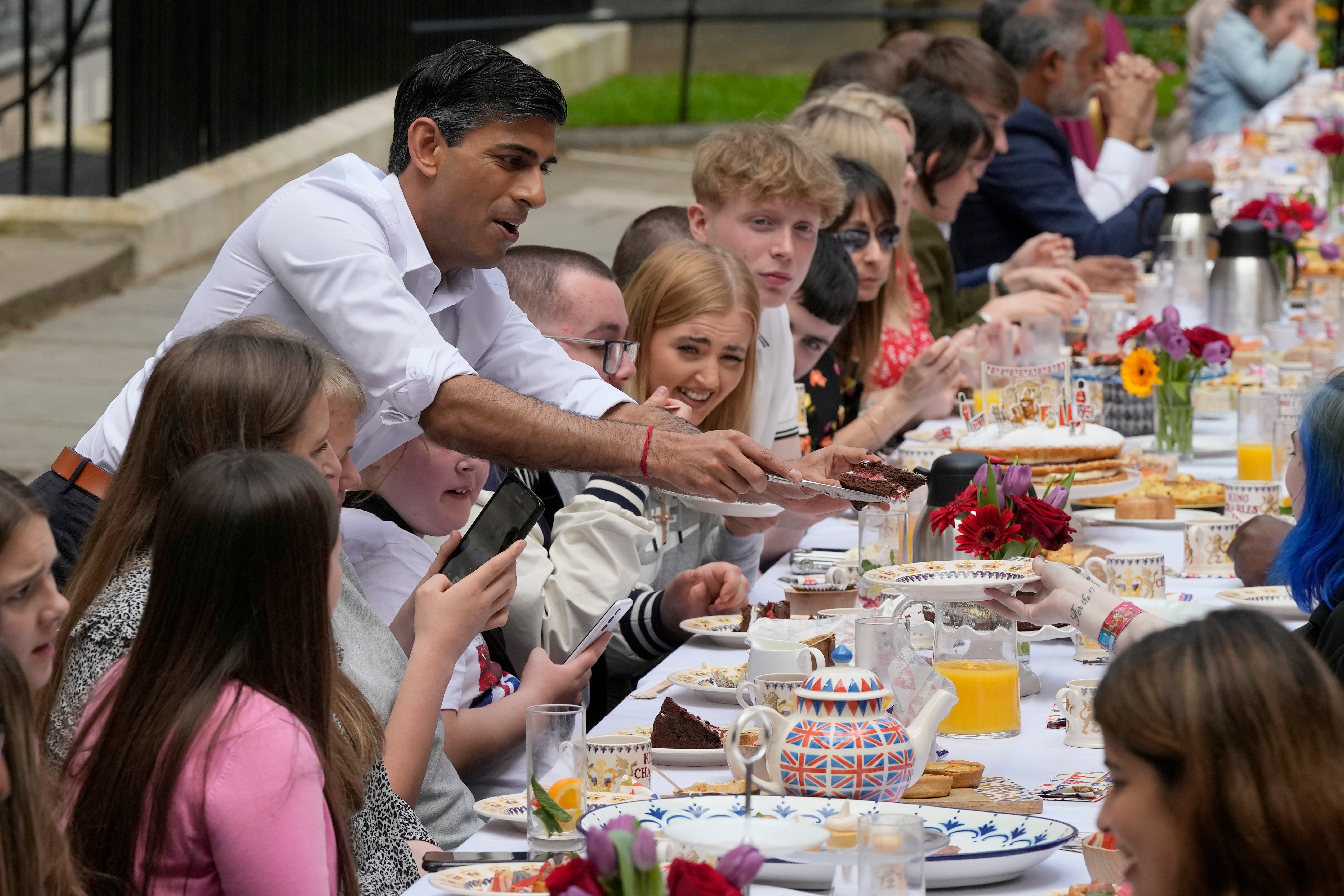 The prime minister slices cake for guests at a street party in Downing Street