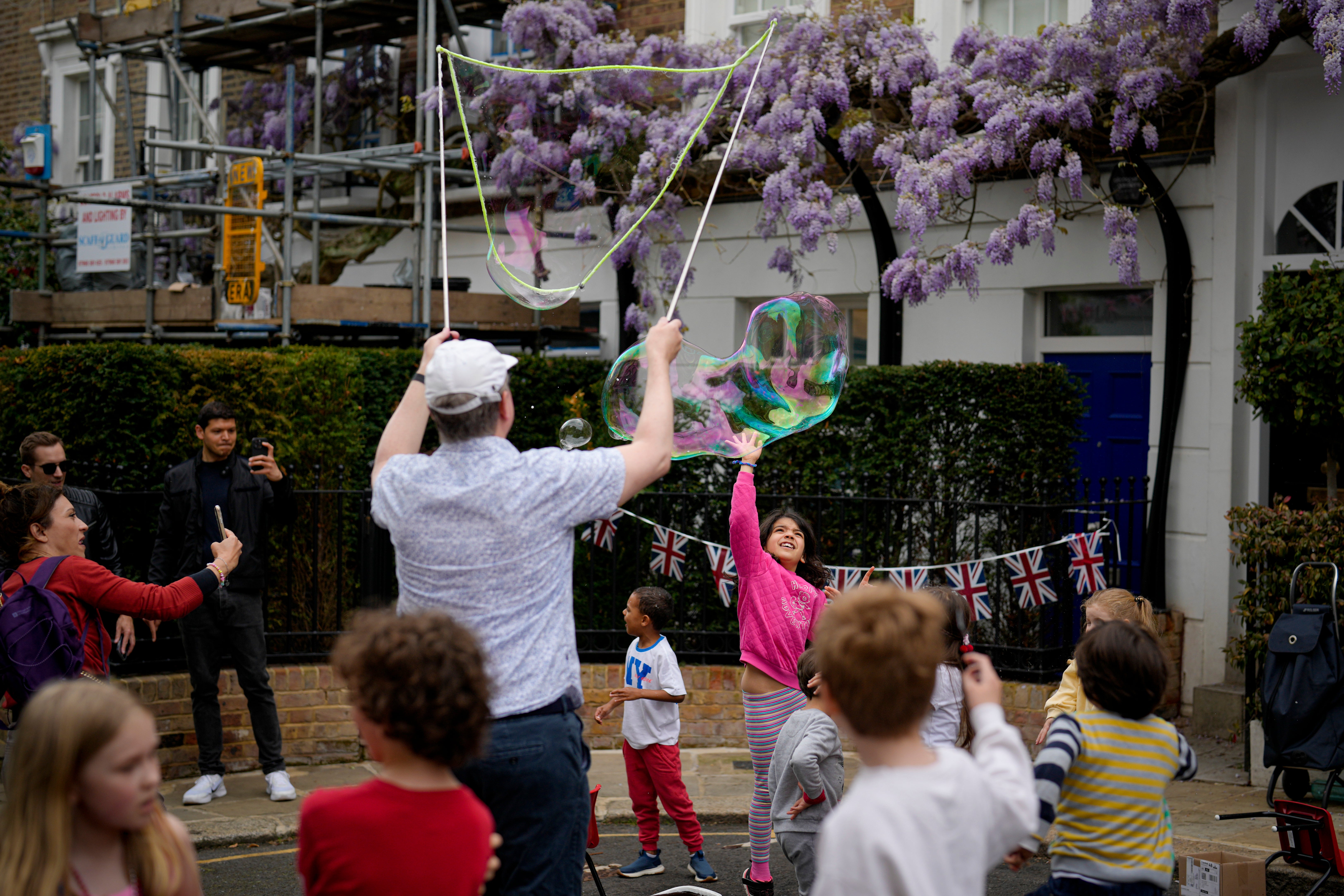 A child jumps to pop a soap bubble during the Big Lunch celebrations on Holland Street in London