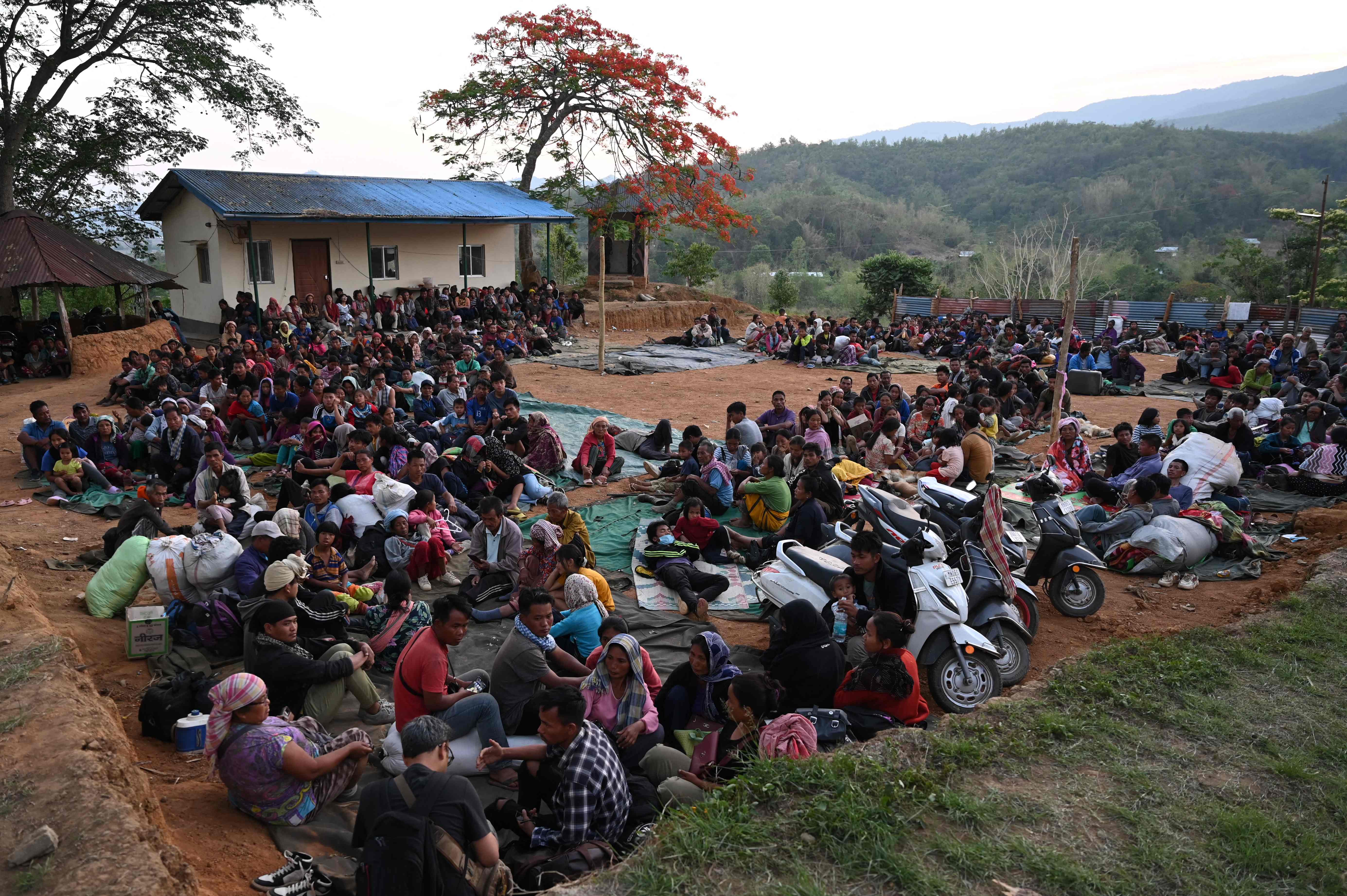 People wait at a temporary shelter in a military camp, after being evacuated by the Indian army on 7 May, as they flee ethnic violence