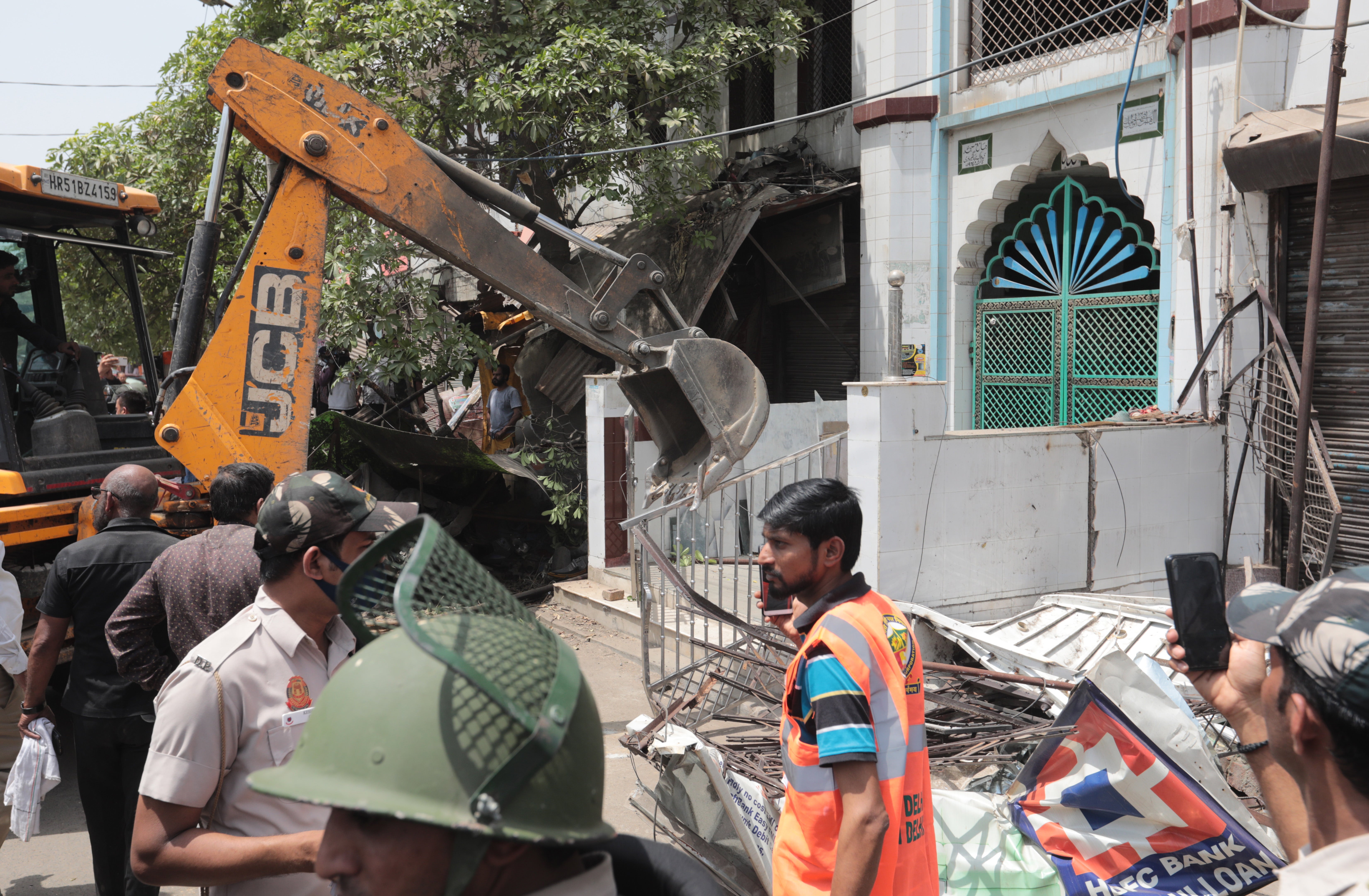 A bulldozer dismantles structures outside a mosque during the demolition drive of illegal structures in Delhi’s violence-hit Jahangirpuri