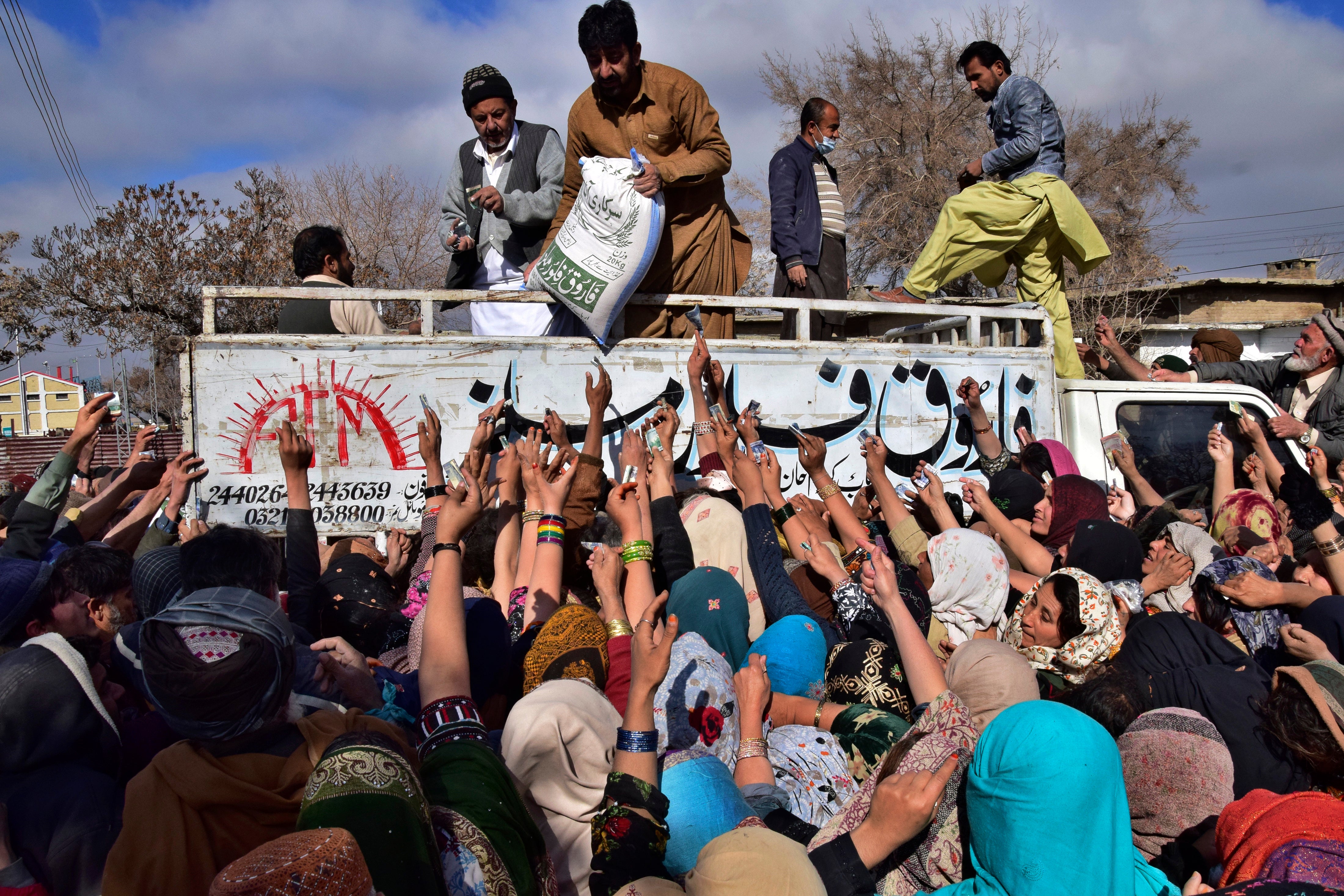 People jostle each other to buy subsidised sacks of wheat flour in Quetta, Pakistan, amid heatwaves and flood displacement