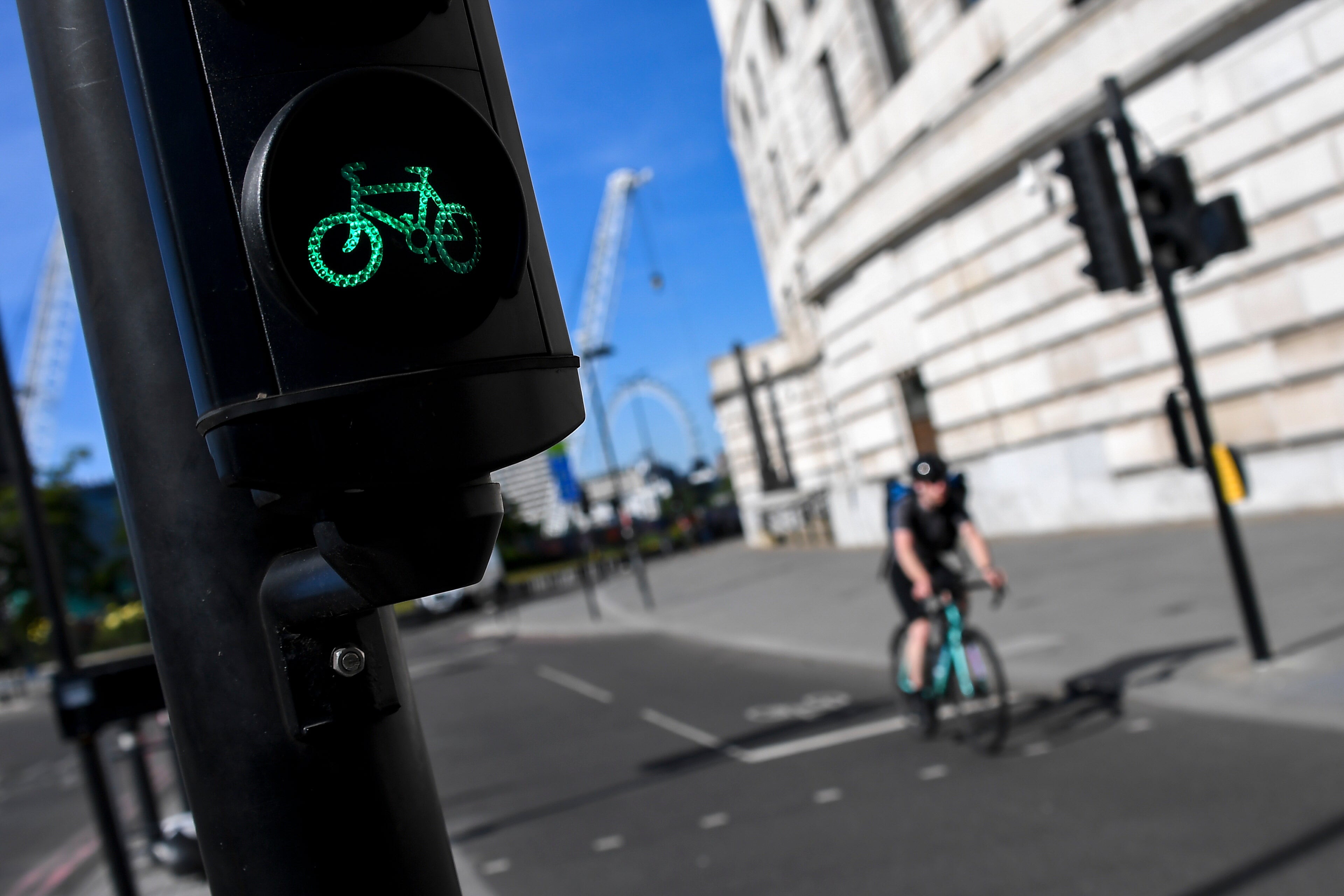 <p>A man rides his bicycle past a green traffic light, in London</p>