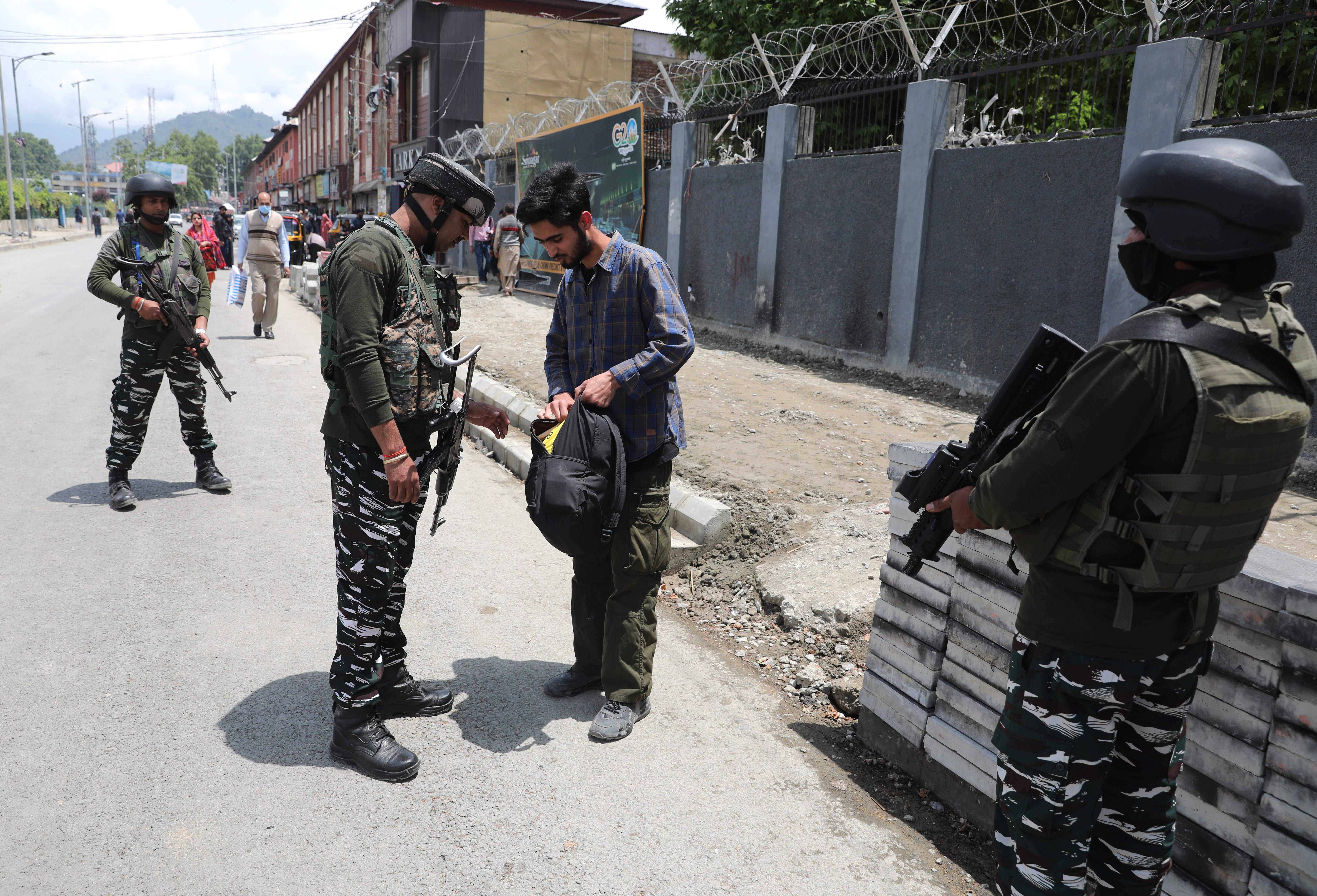 An Indian paramilitary soldier checks bag of a Kashmiri man during a surprise search operation as security is being beefed up ahead of the G20 meetings