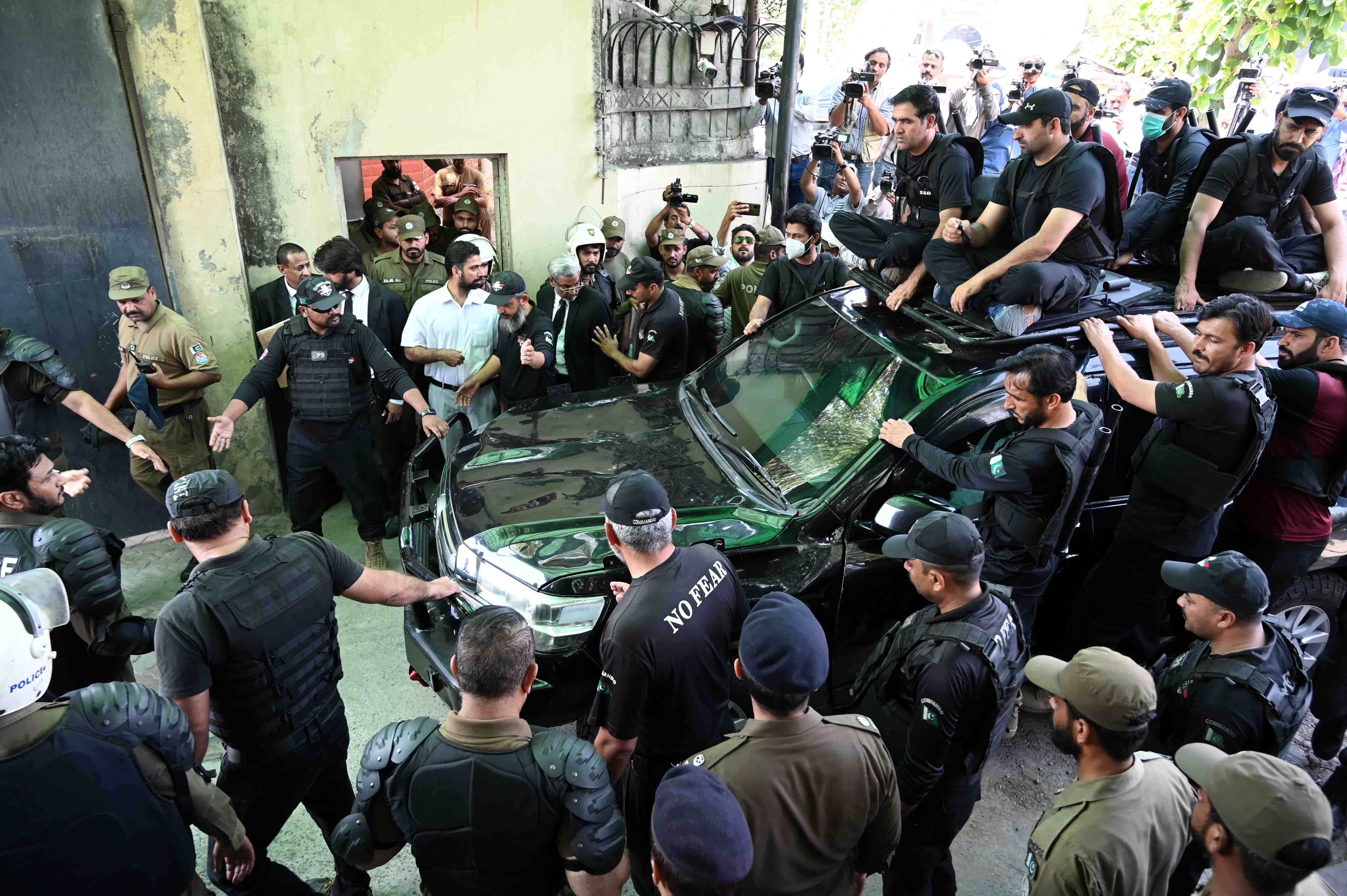 Private security members escort former Prime Minister Imran Khan (in vehicle) as he appears before a court to get extension in bails