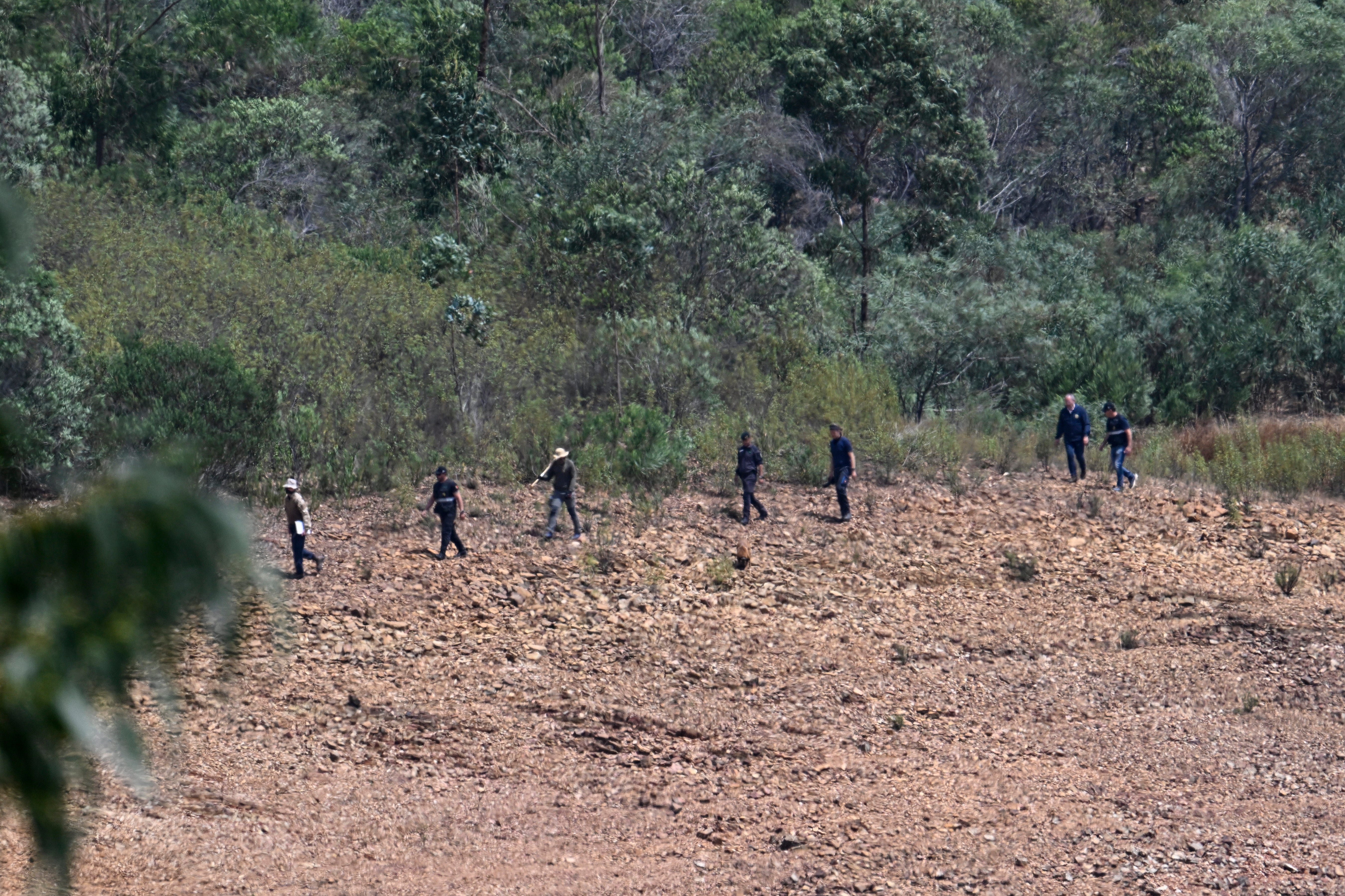 German and Portuguese Judiciary police members walk with a sniffer dog at the search area