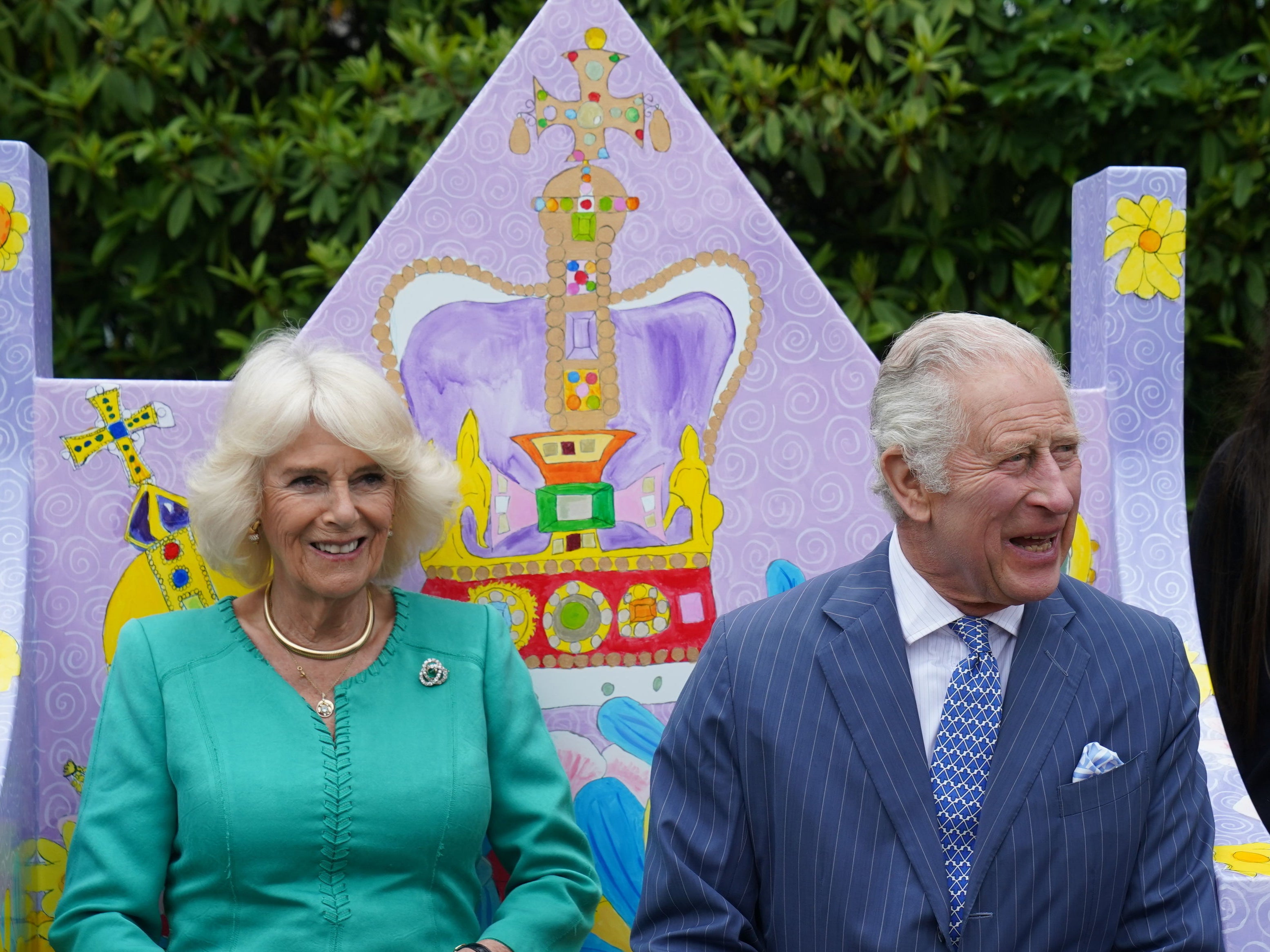 King Charles III and Queen Camilla take a seat on a bench designed by pupils from Belfast's Blythefield Primary School who have taken part in Historic Royal Palaces' competition to design Coronation benches at Hillsborough Castle