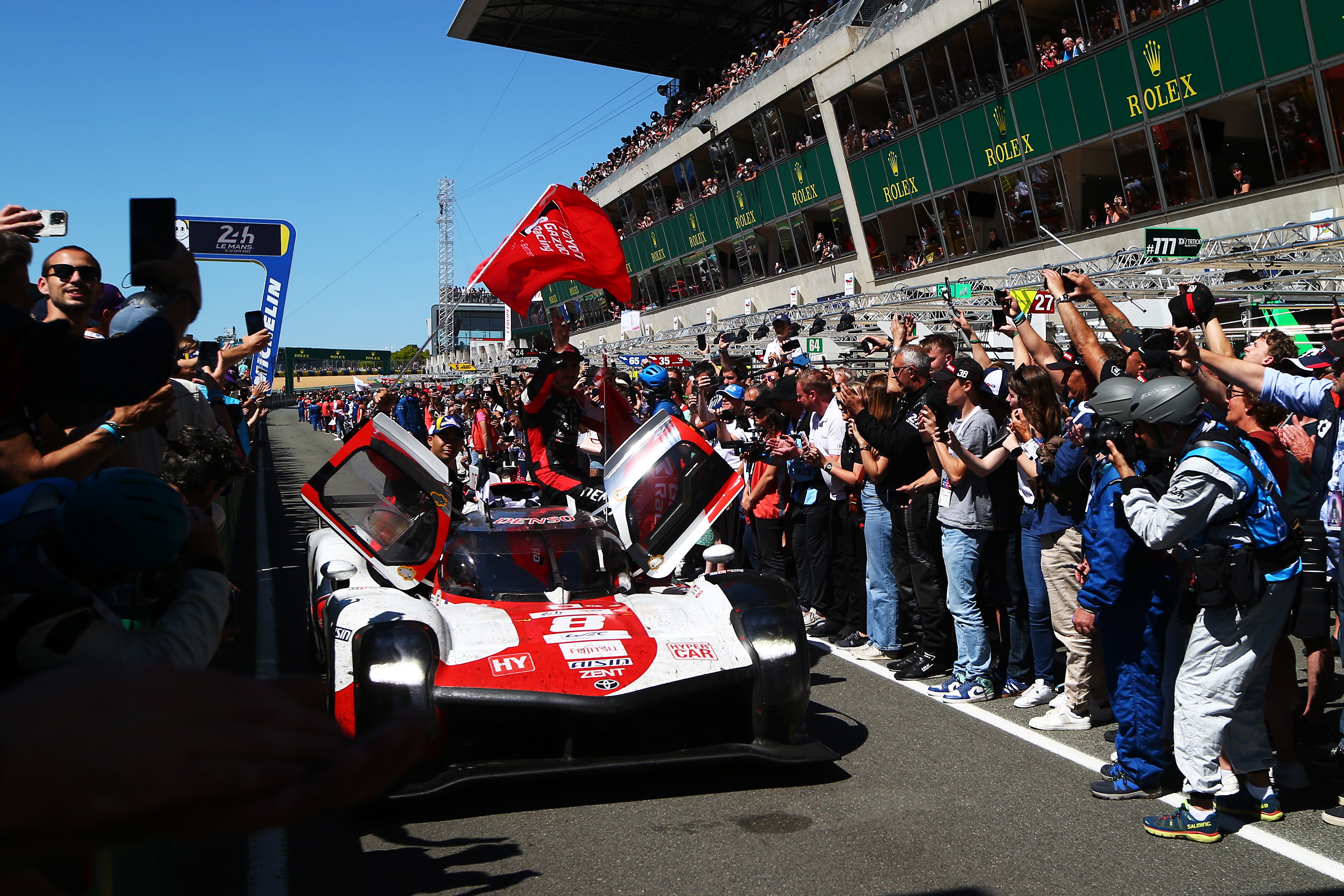 The Toyota Gazoo Racing GR010 Hybrid team of Sebastien Buemi, Brendon Hartley and Ryo Hirakawa celebrate as they drive down the pitlane after winning the 2022 race